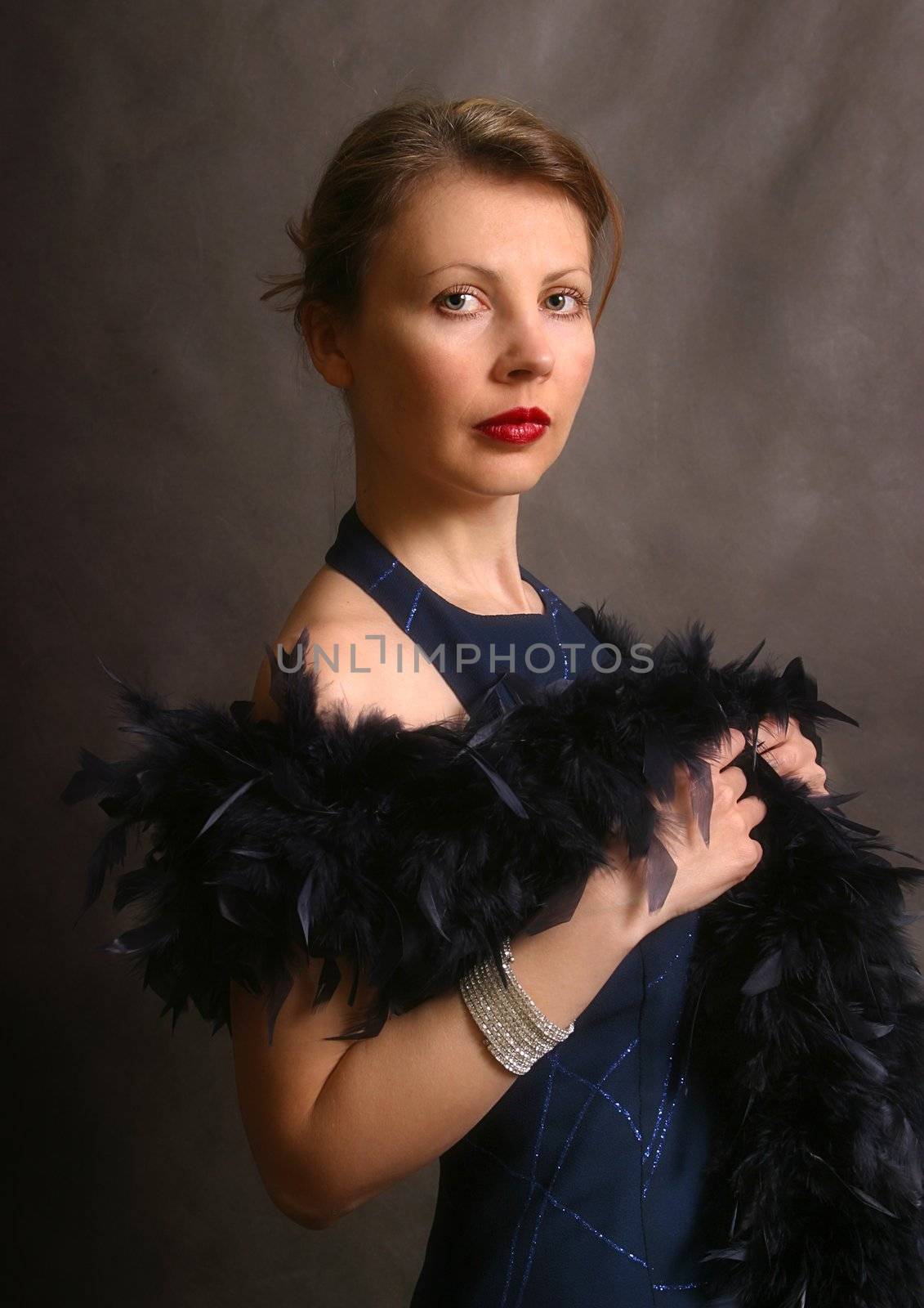 Portrait of the beautiful woman in an evening dress with feathers