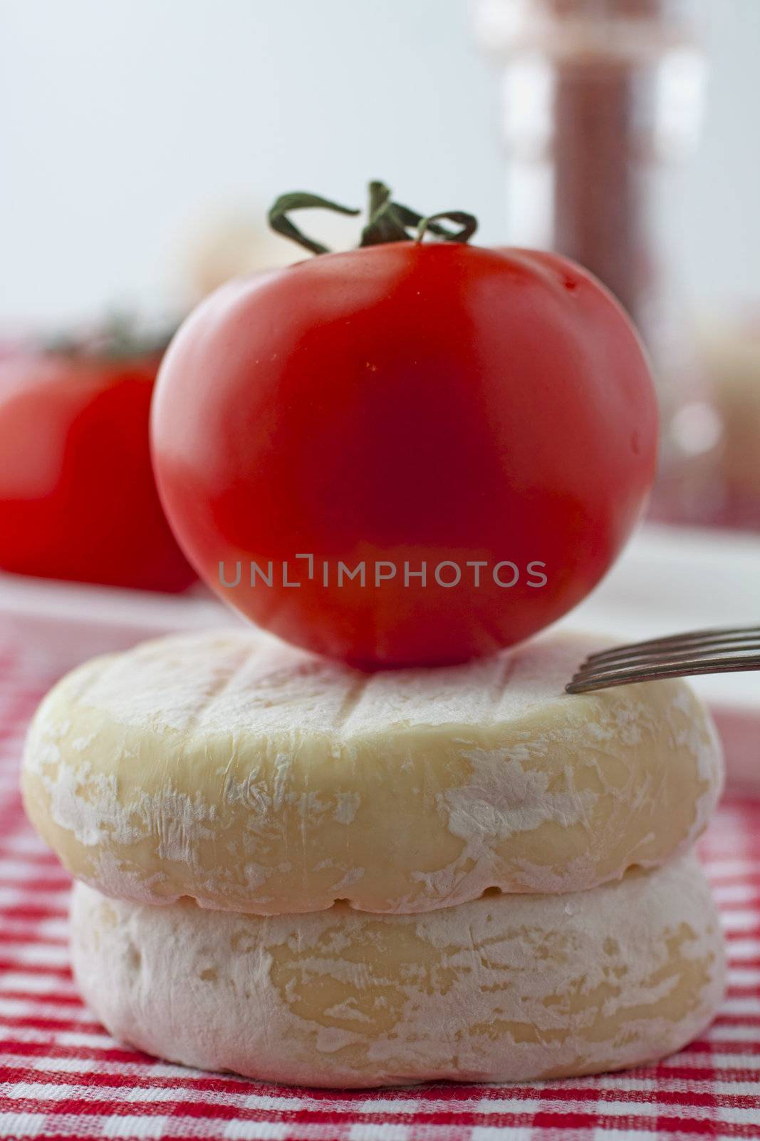 Tomato over two pieces of cheese over red and white cloth
