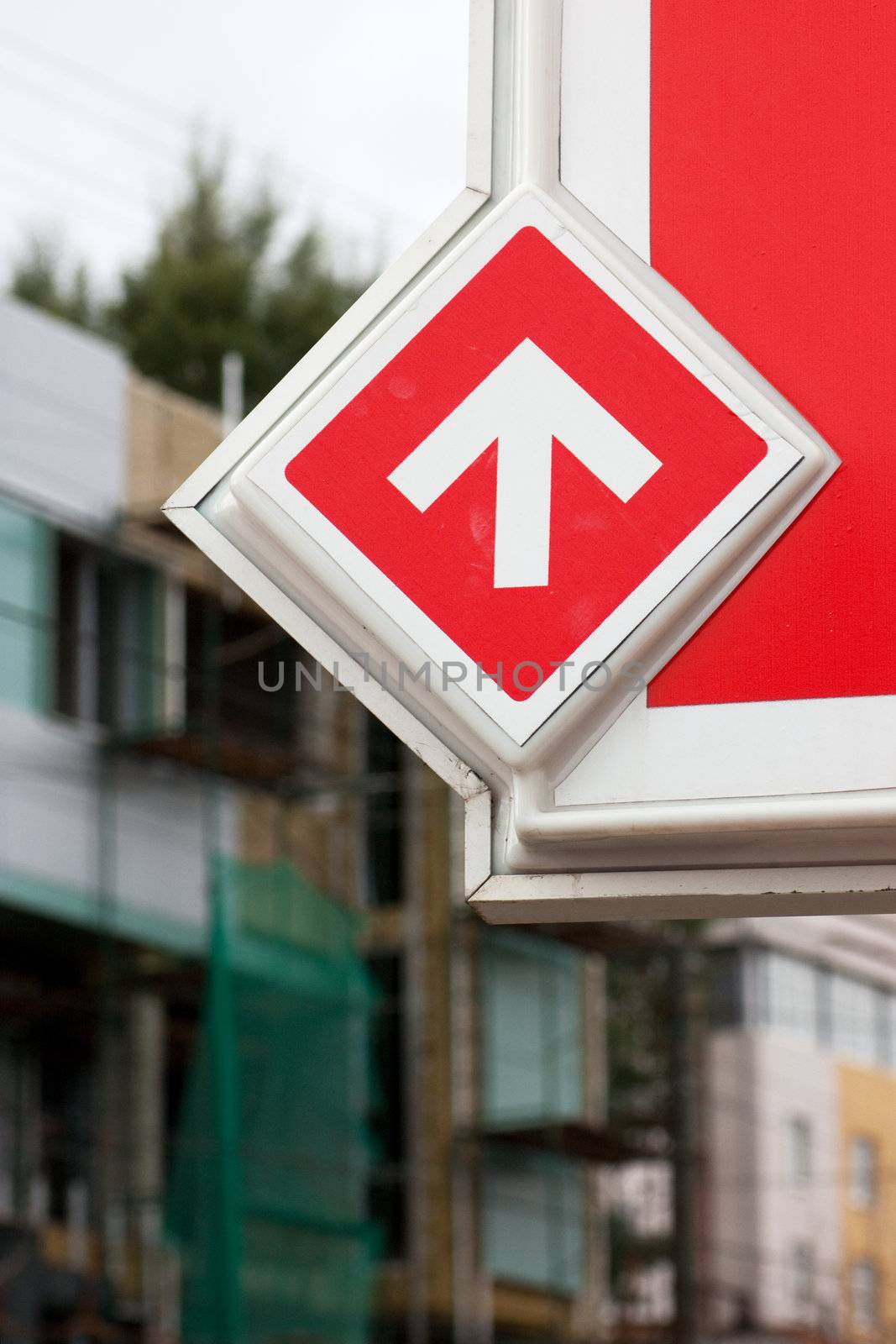 Closeup view of road sign. White arrow over red background. One direction.