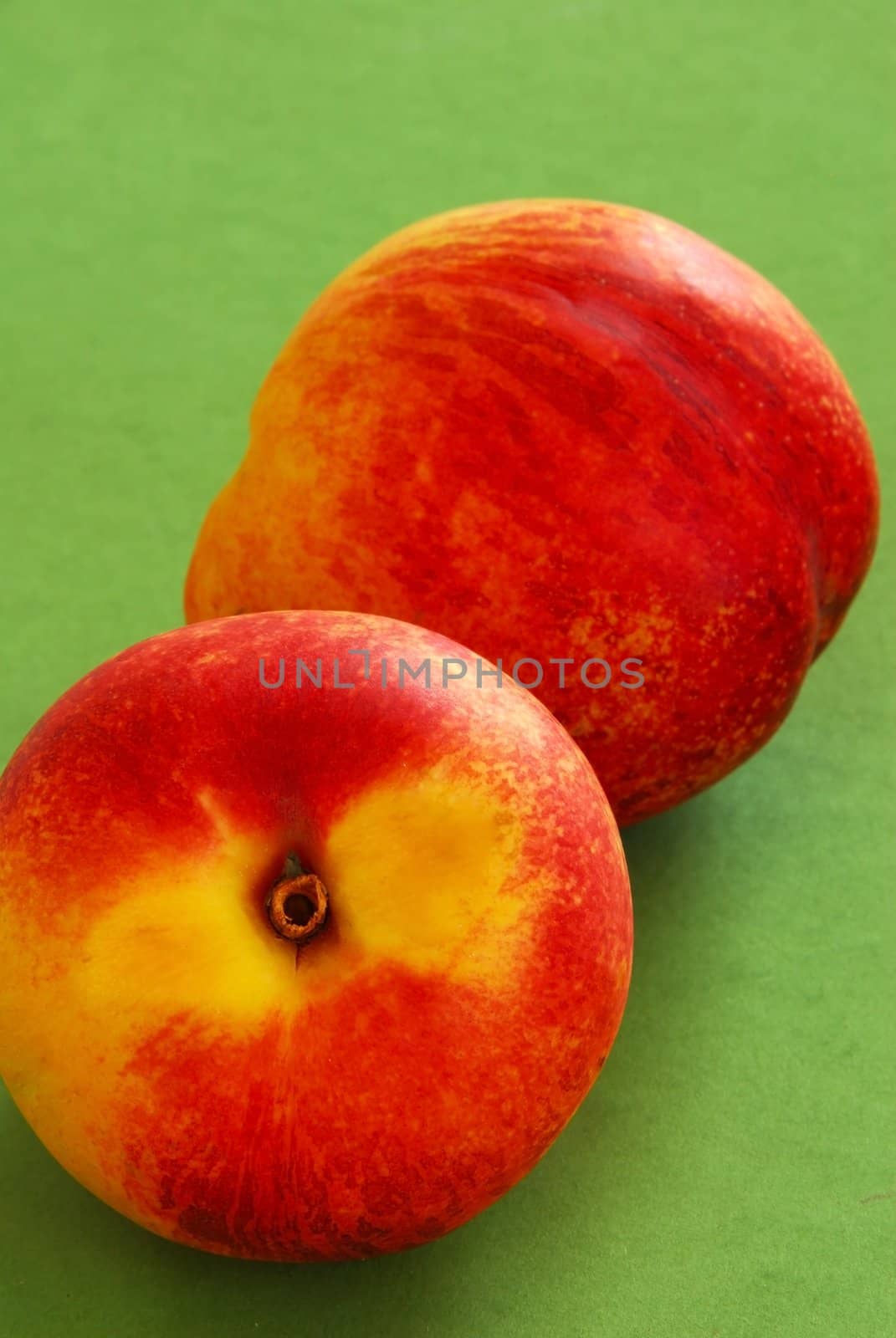 two ripe peaches on the green background