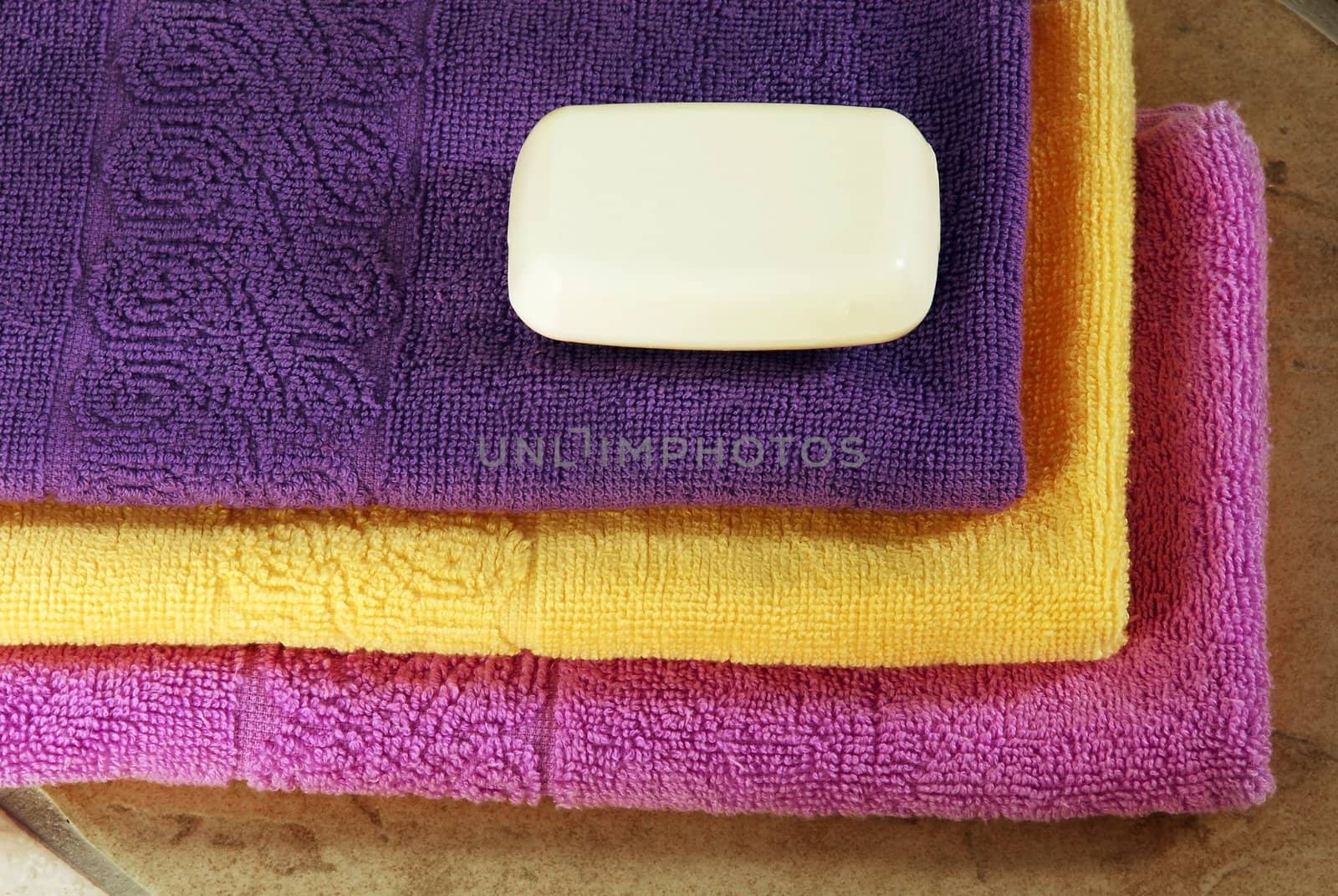 pile of purple, yellow and magenta towels with white soap