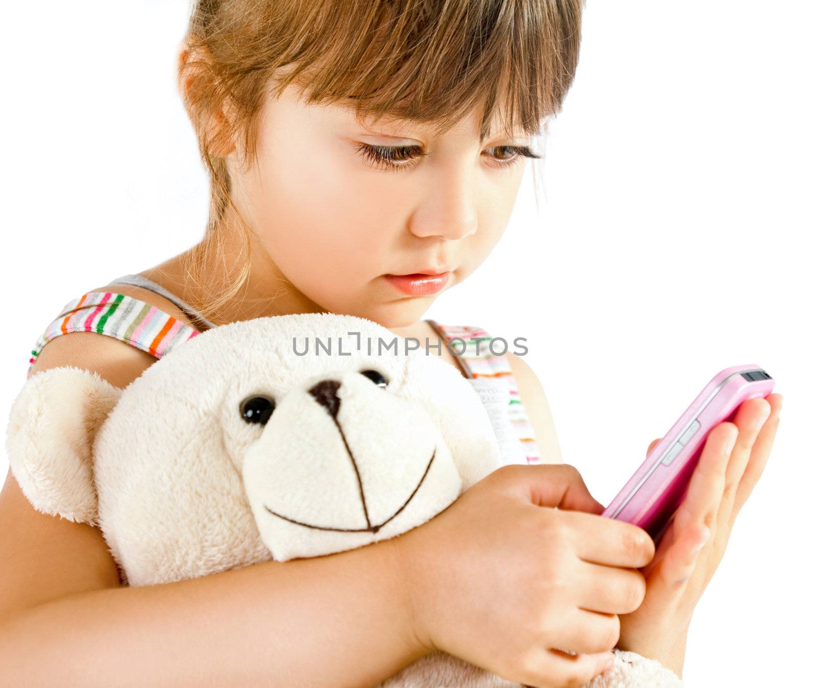 Sweet little girl cuddling teddy bear holding pink mobile phone, isolated on white