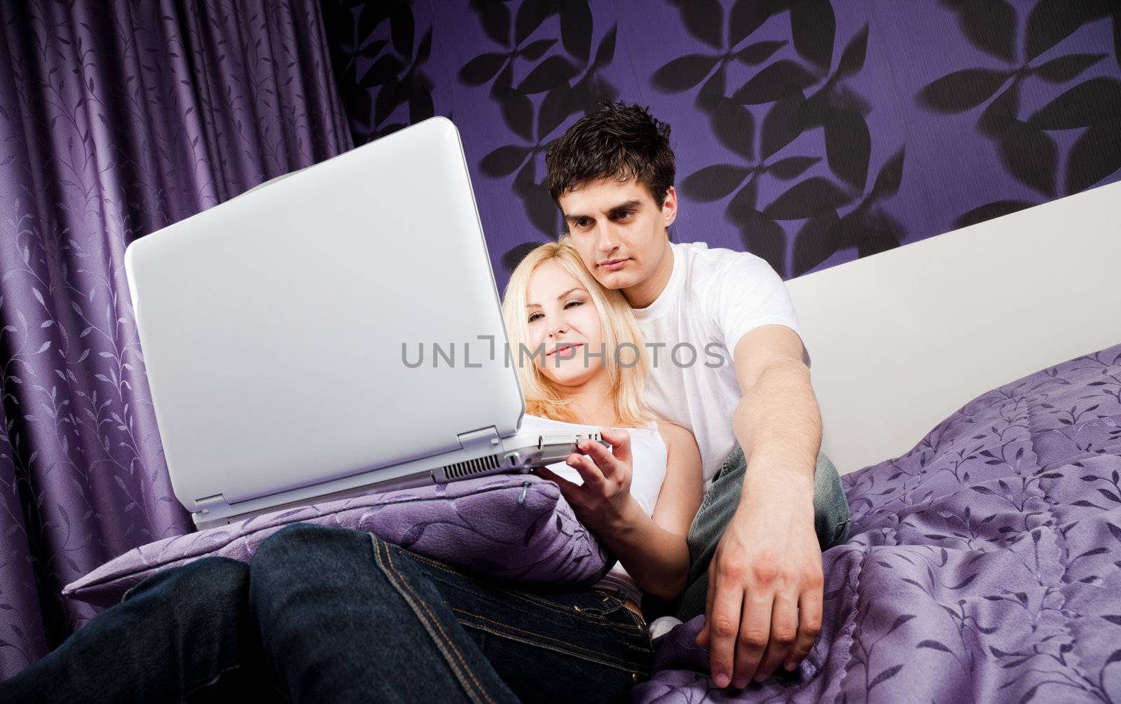 Young couple lying on bed behind laptop