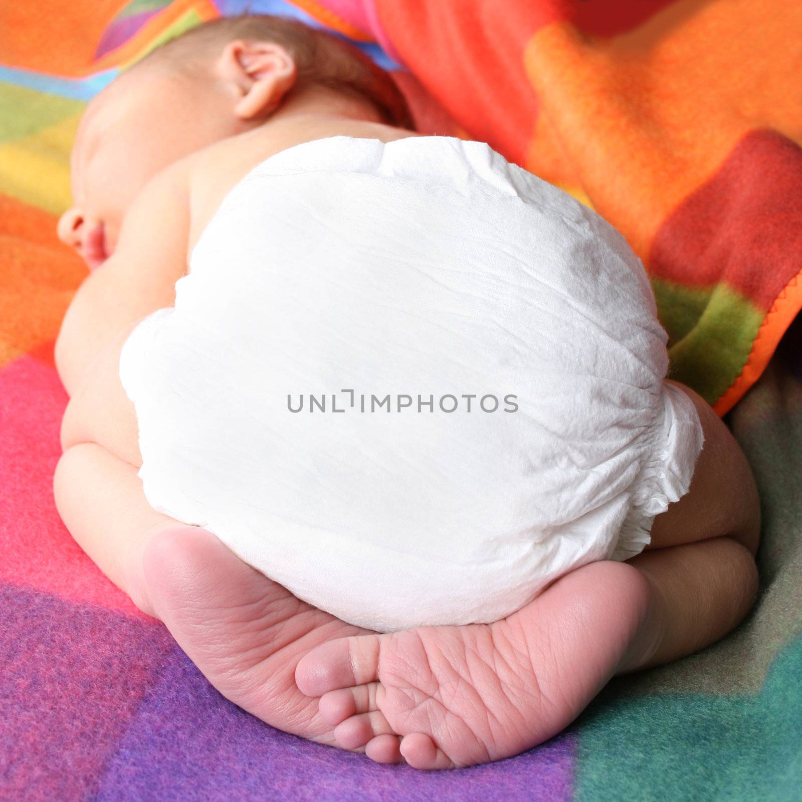 Newborn baby lying on his stomach with his feet folded