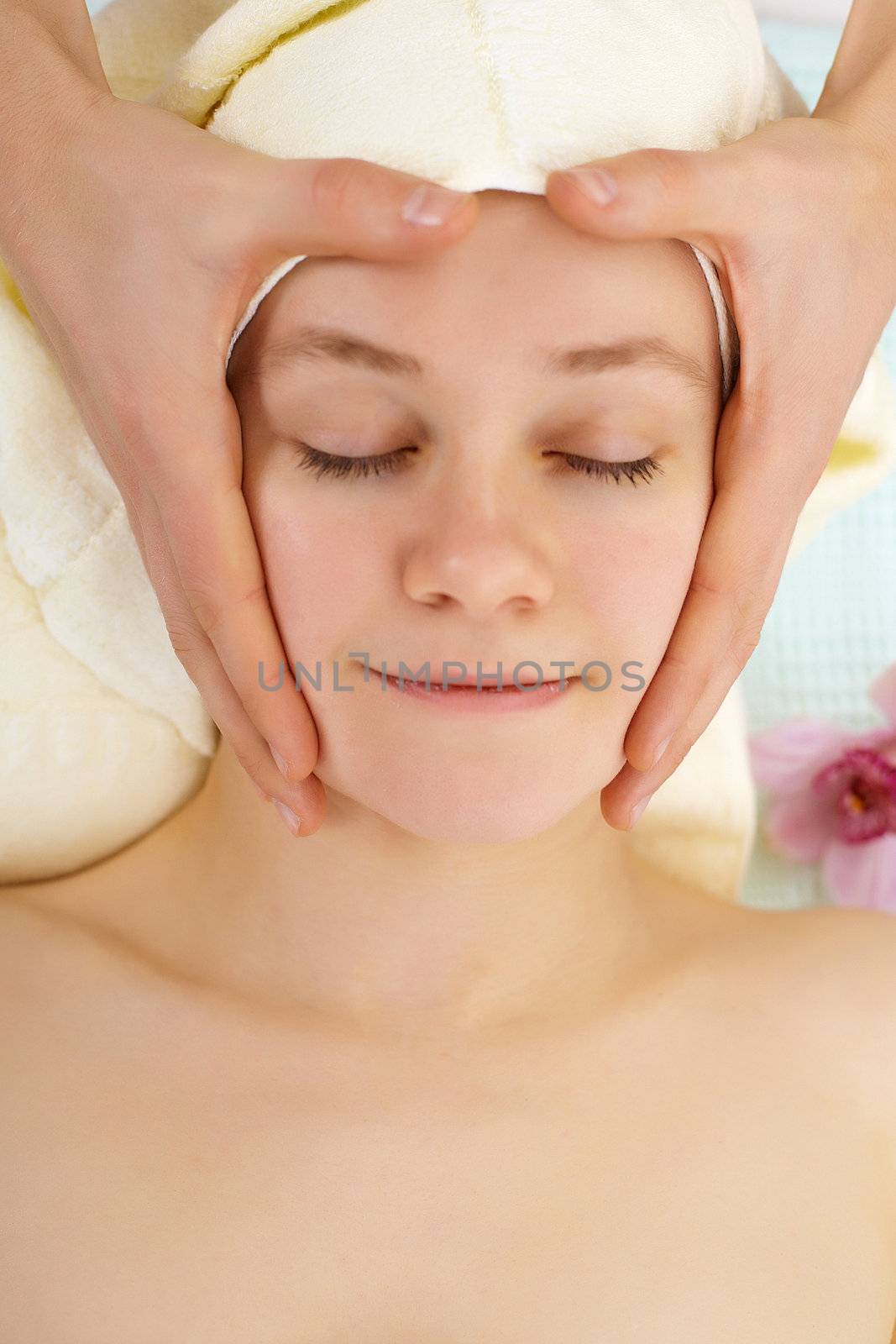 Man's hands do woman's face massage in salon