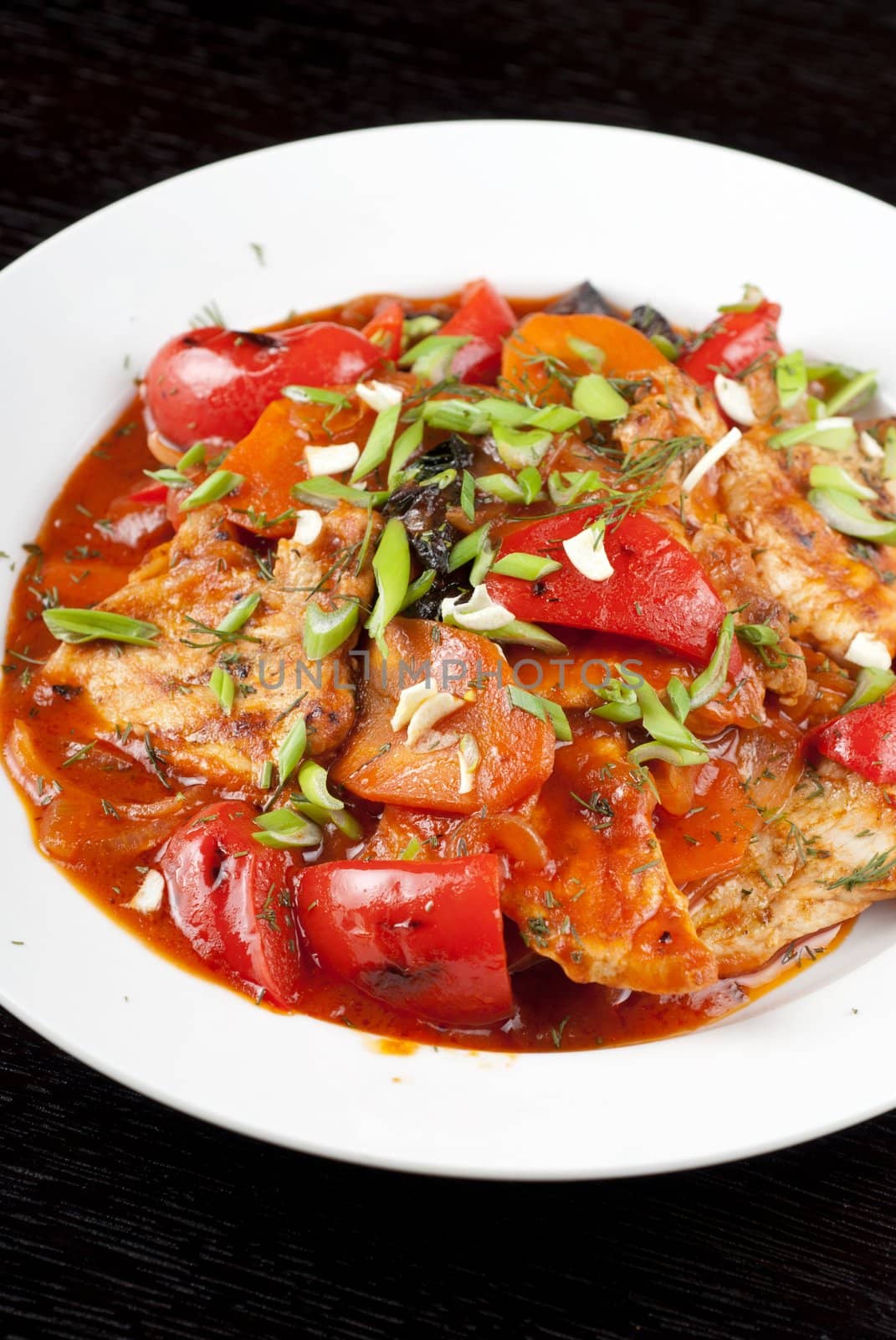 pork meat with tomato, pepper, prunes, garlic and green onion