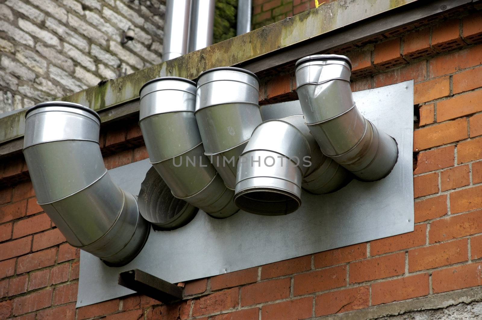 Pipes of ventilation are located on a wall of a building