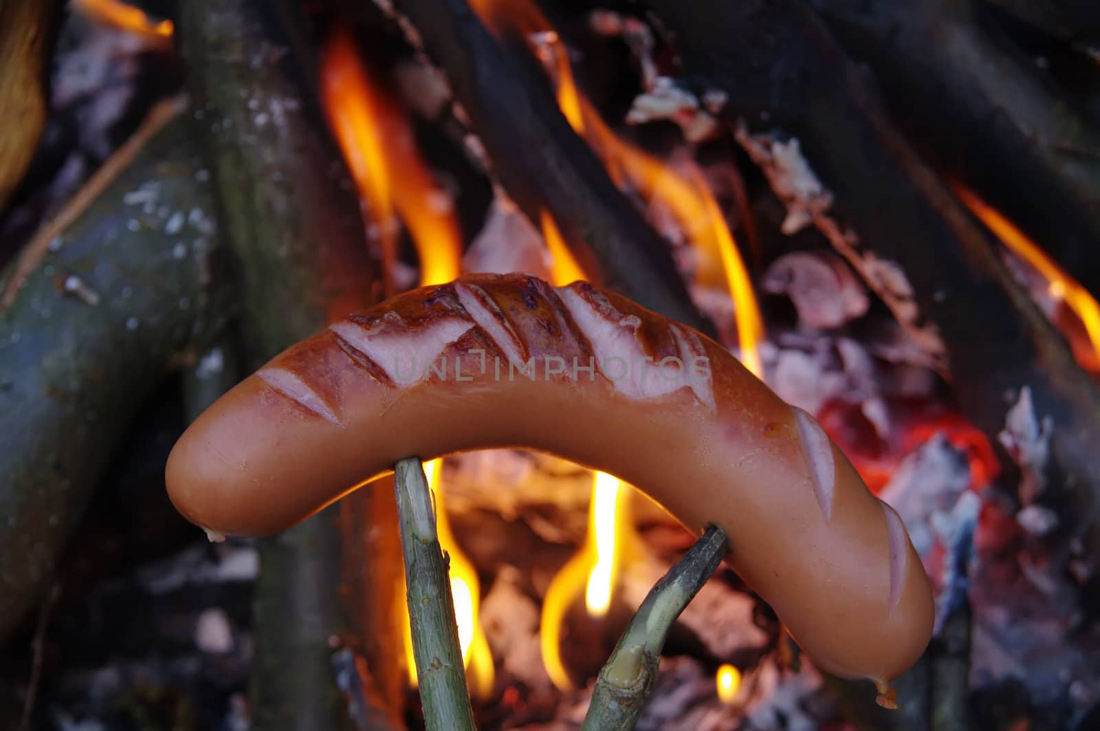 a sausage grilled on a camp fire