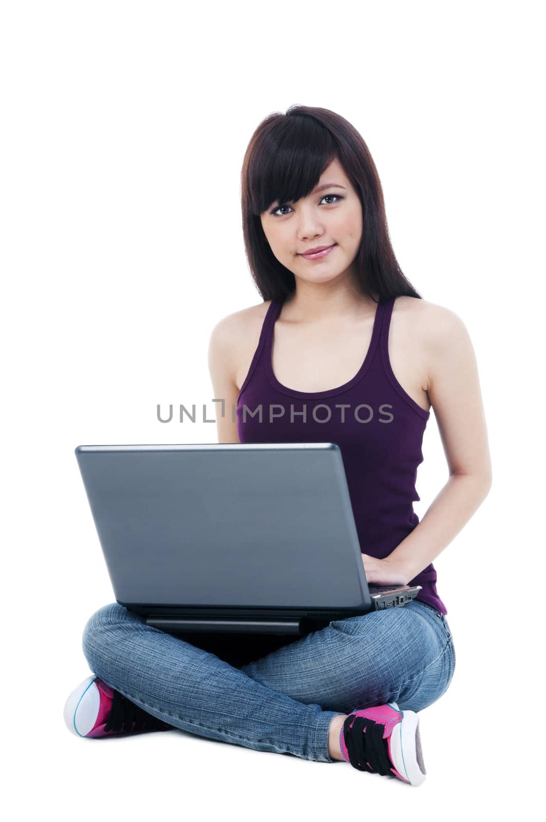 Portrait of an attractive girl sitting on floor using laptop over white background.