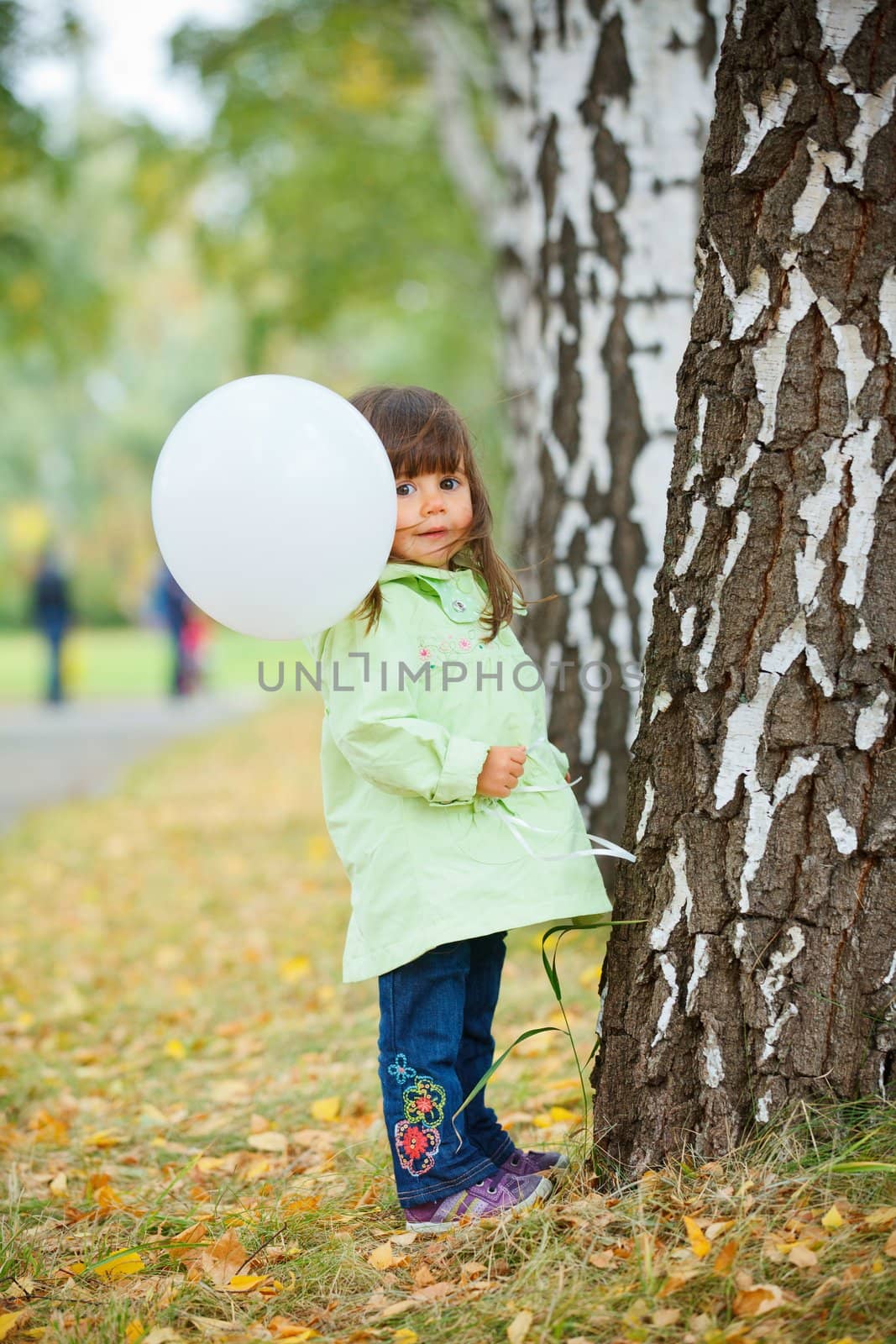 Pretty little girl with a white balloon walking in the park