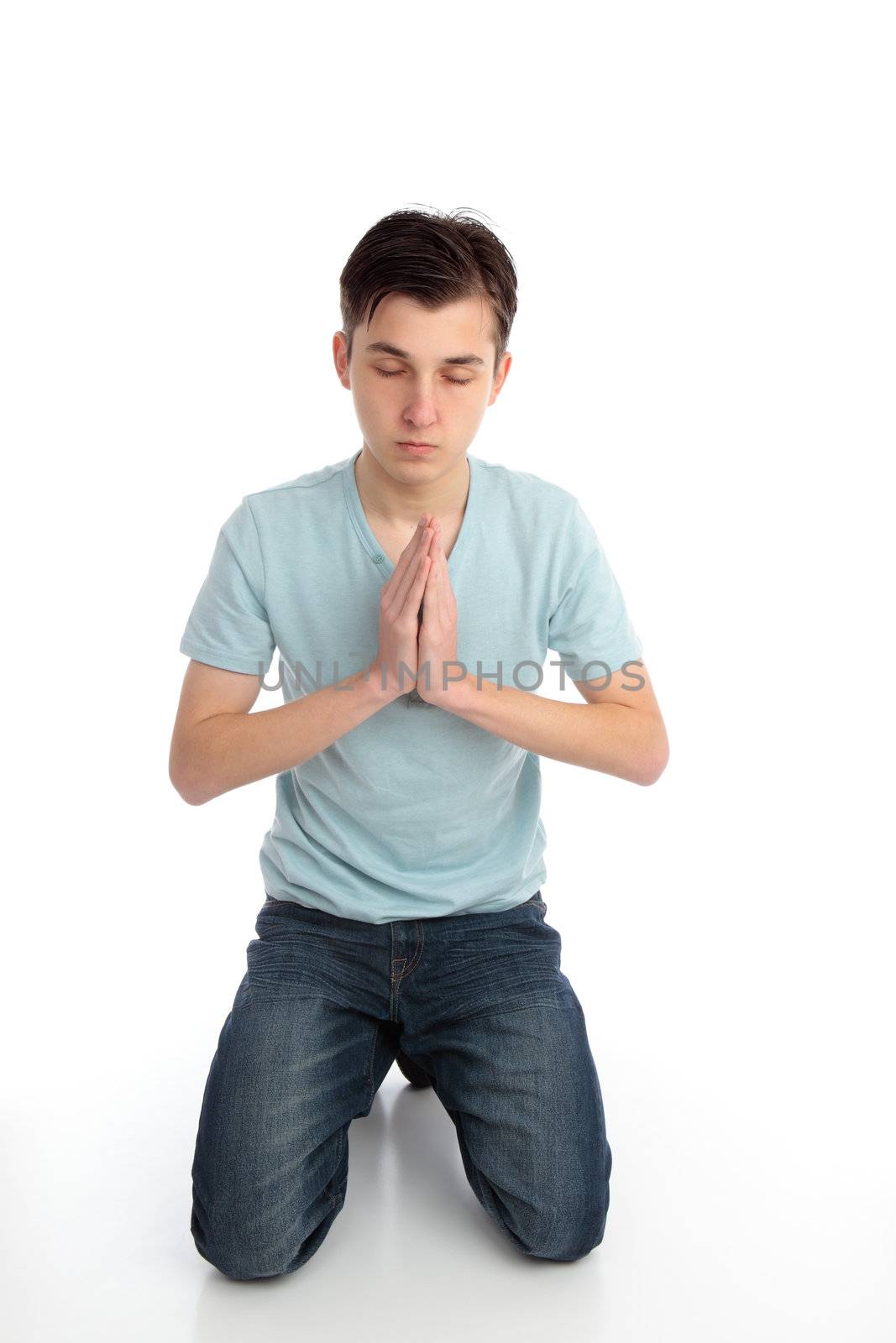 A teenager kneeling in quiet prayer.  White background.