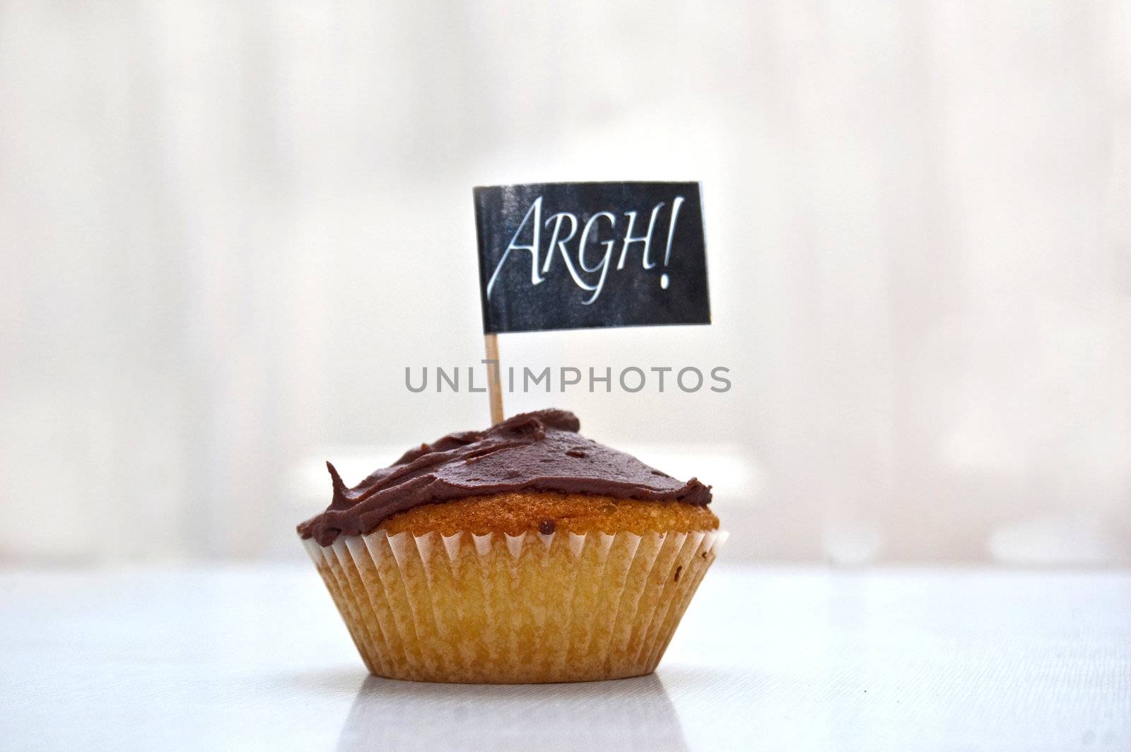 an image of a party cup-cake with a flag saying argh! over white with copyspace.