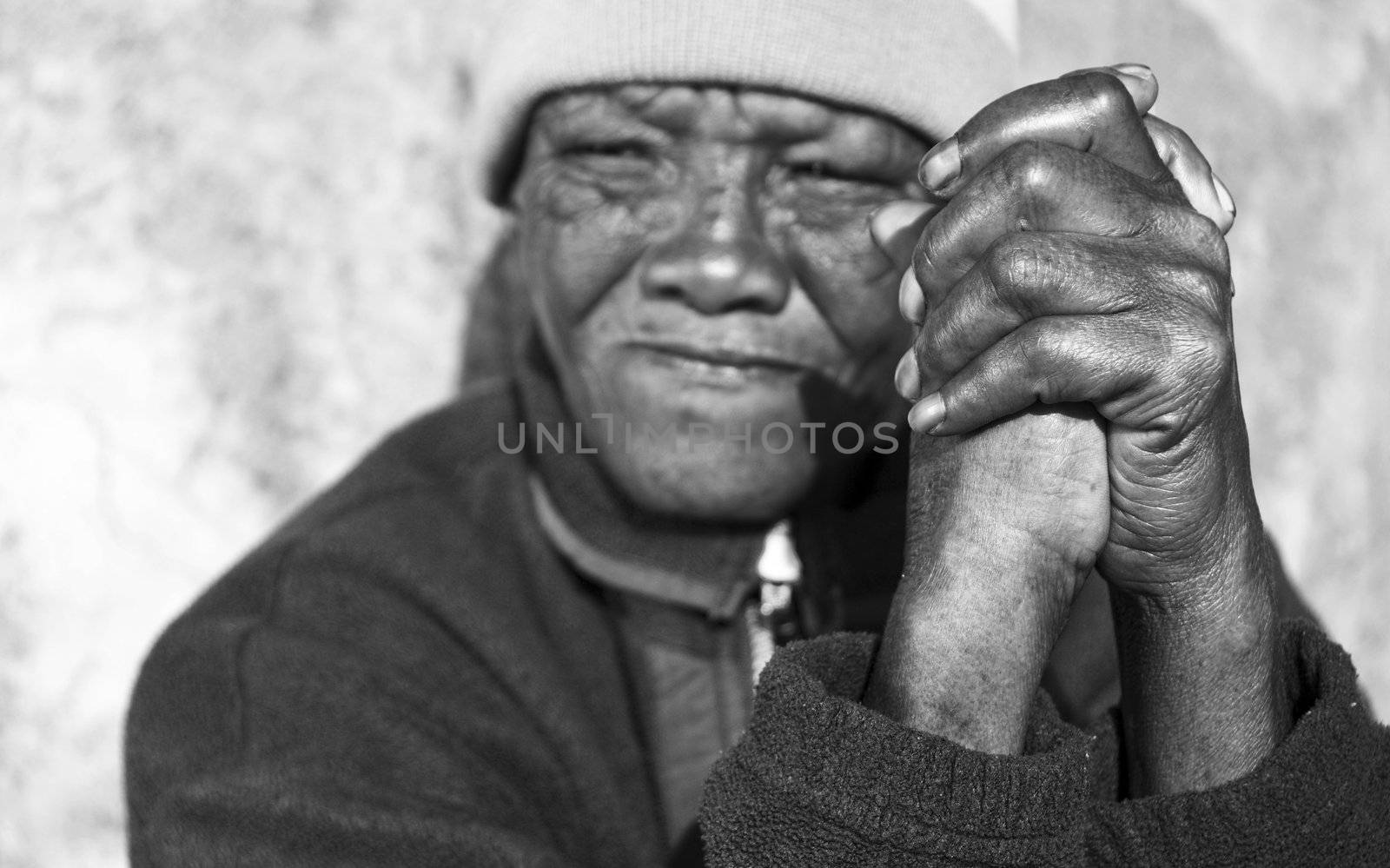 Black and white photo of an senior african woman with folded hands - focus on the weathered hands