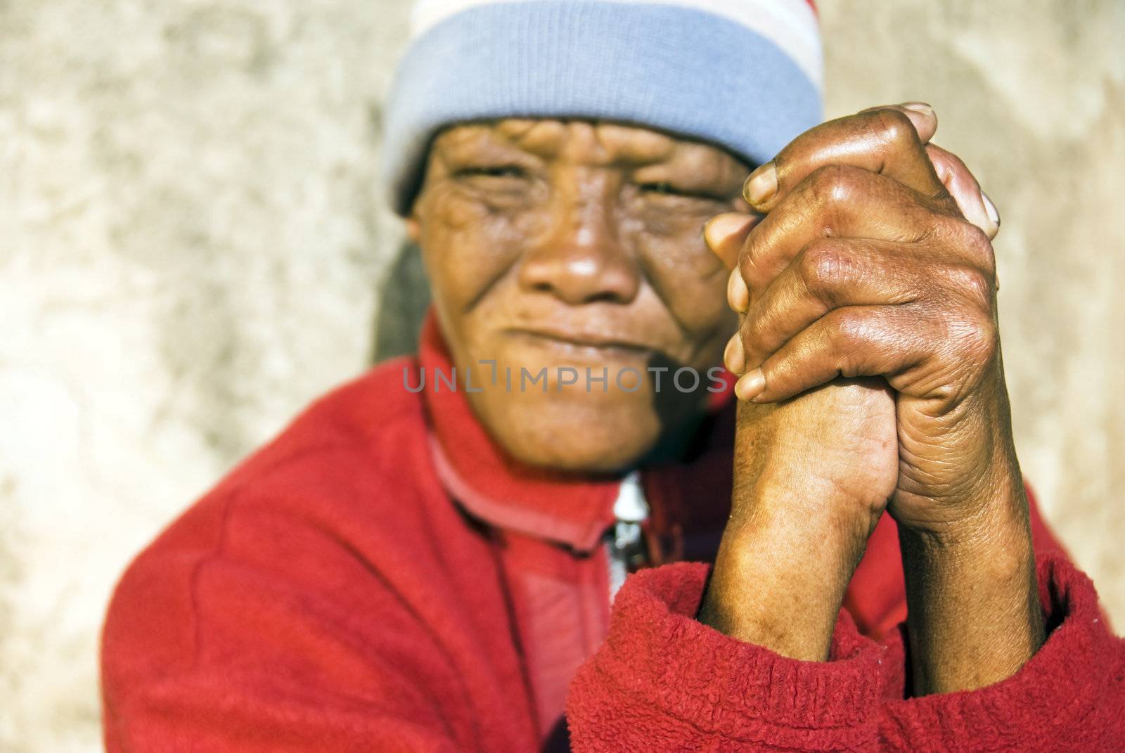 An old African woman with folded hands - focus on the weathered hands