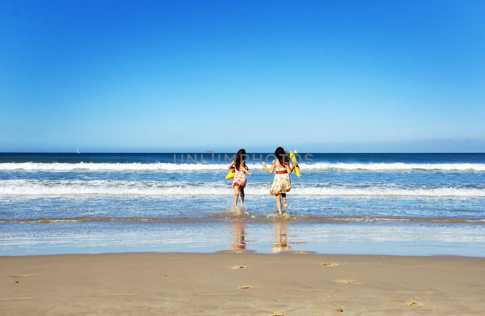 Two young woman having fun on the beach on a summer day