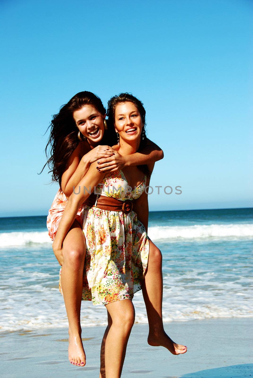 Two young woman having fun on the beach on a summer day by tish1
