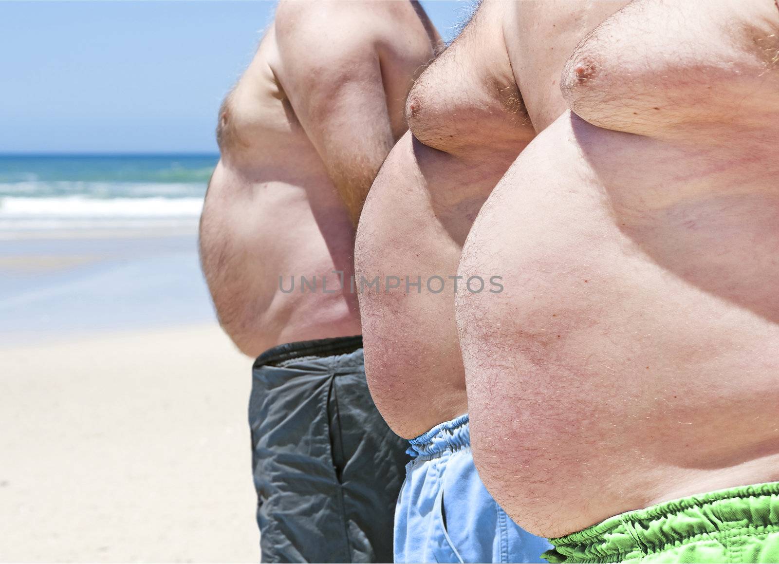 Close up of three obese fat men of the beach