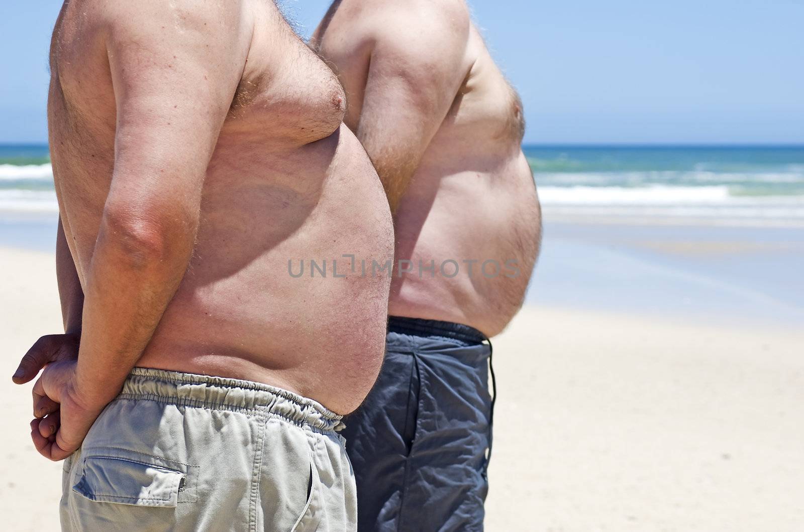 Close up of two obese fat men of the beach