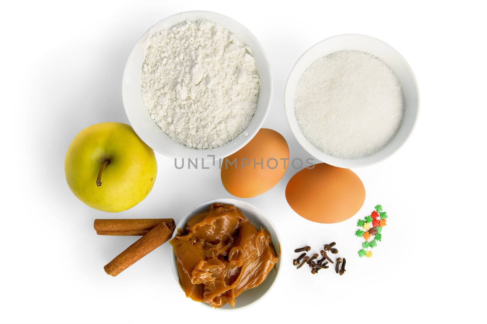 Flour, sugar, condensed milk boiled in a cup, apple, two cinnamon sticks, cloves corn, two eggs and colorful spreading to decorate cakes in isolation on a white background