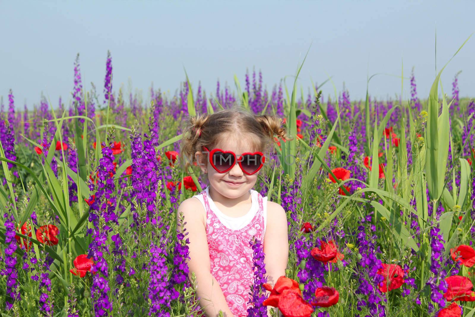 little girl standing in meadow with colorful flowers by goce