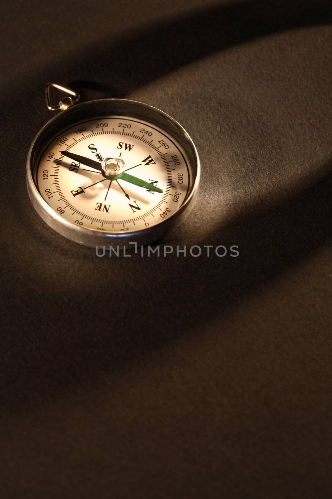 Vintage compass under beam of light on dark background