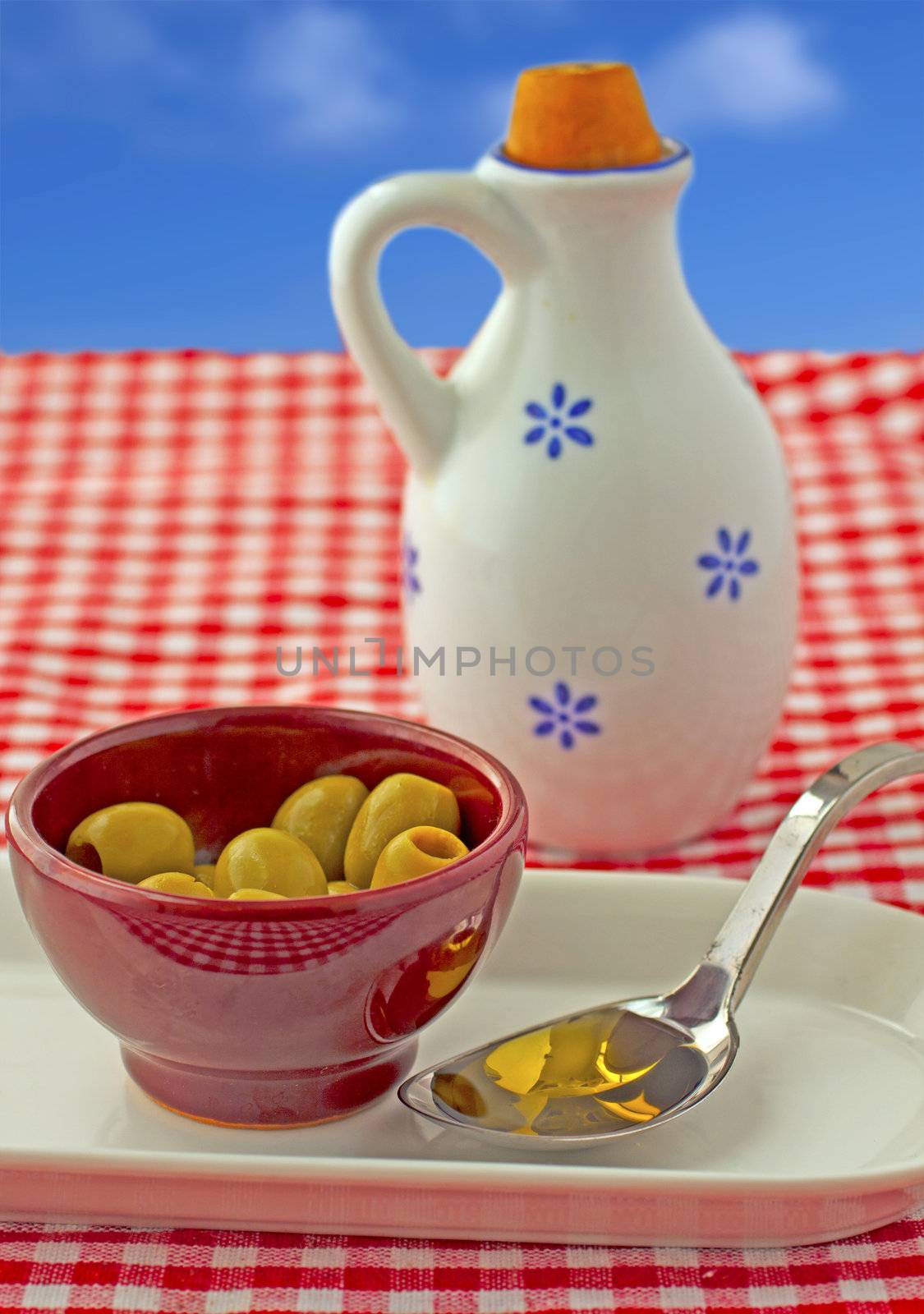 Oil, olives and bottle over a white and red cloth