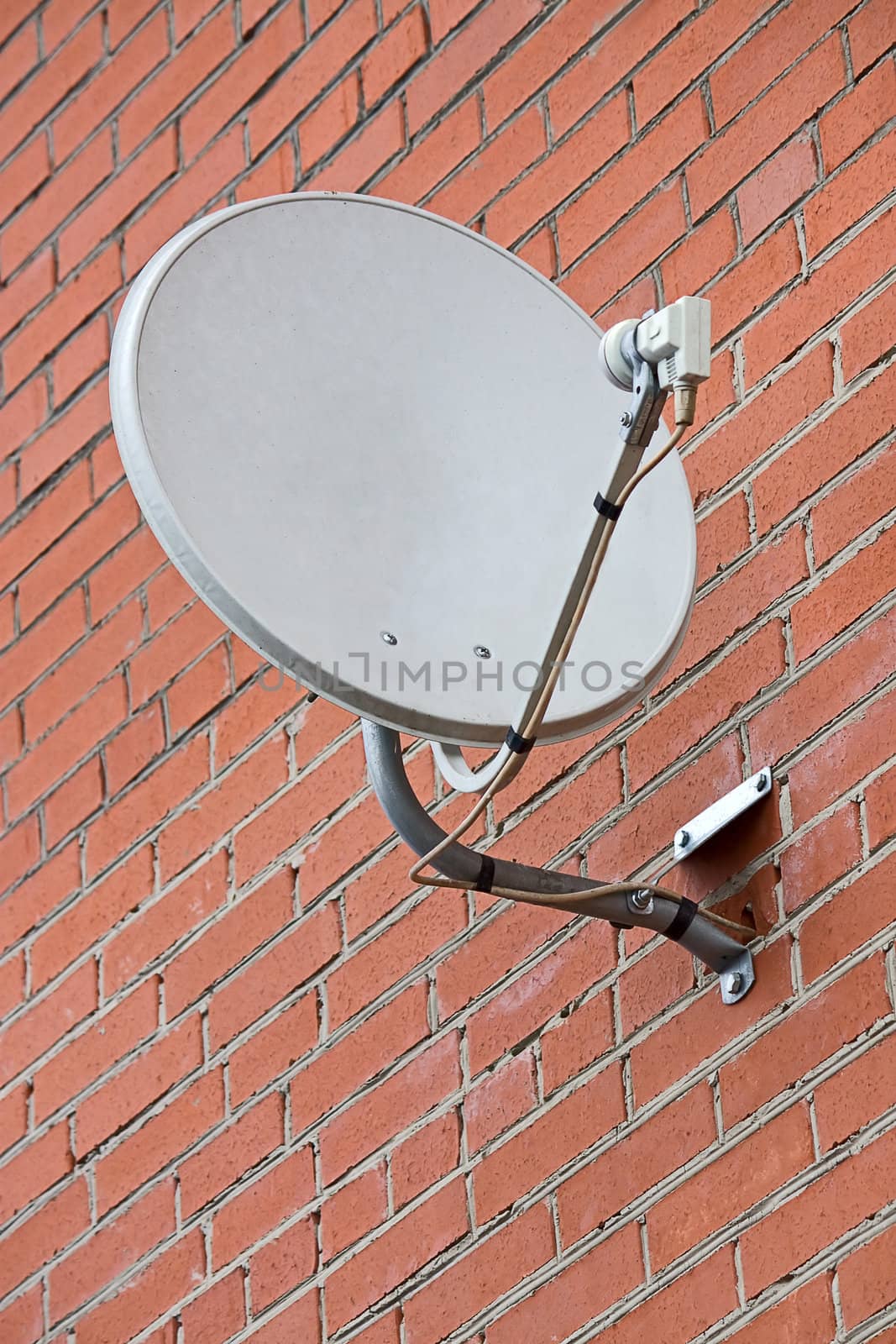 Television satellite dish against a brick wall.