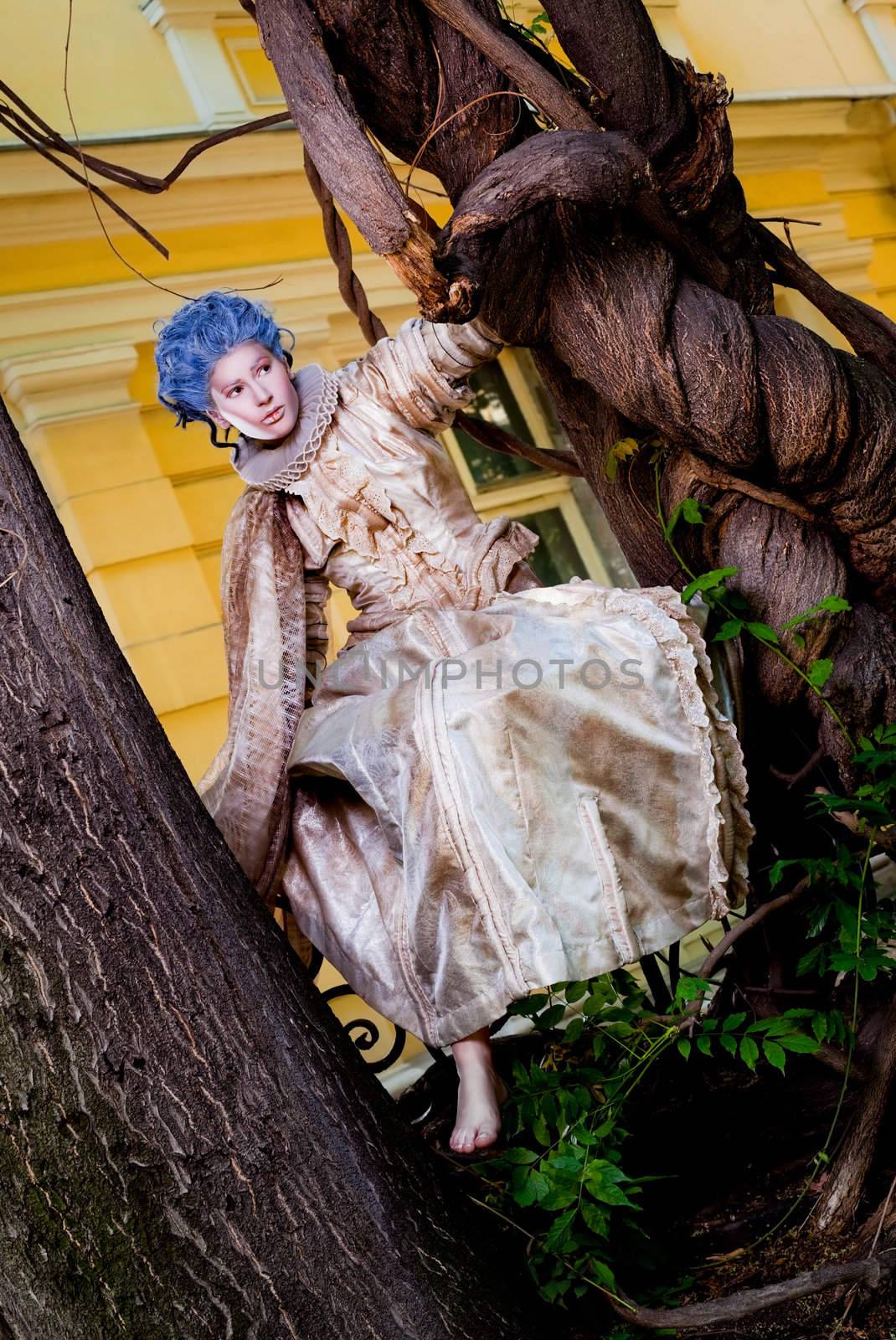 Female with medieval dress and blue wig sitting barefoot on a fence