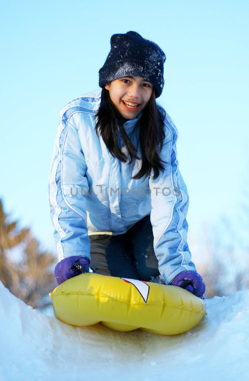 Young teen girl sledding down hill