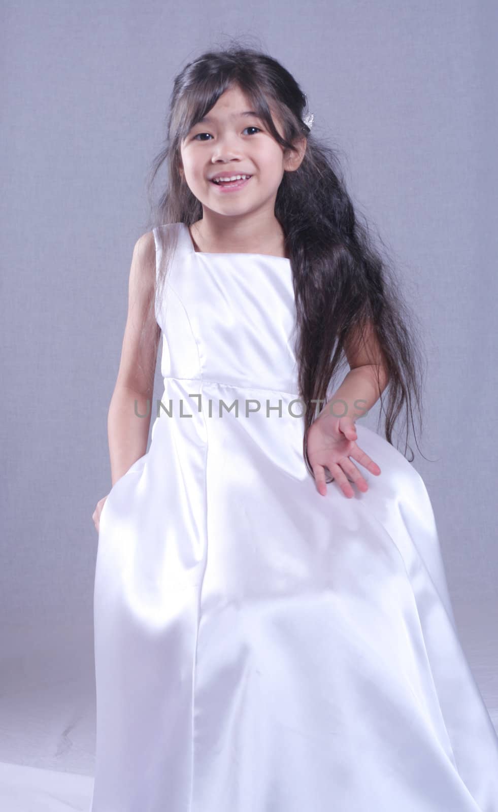 Beautiful little girl in white satin gown . Part Asian, Scandinavian background.