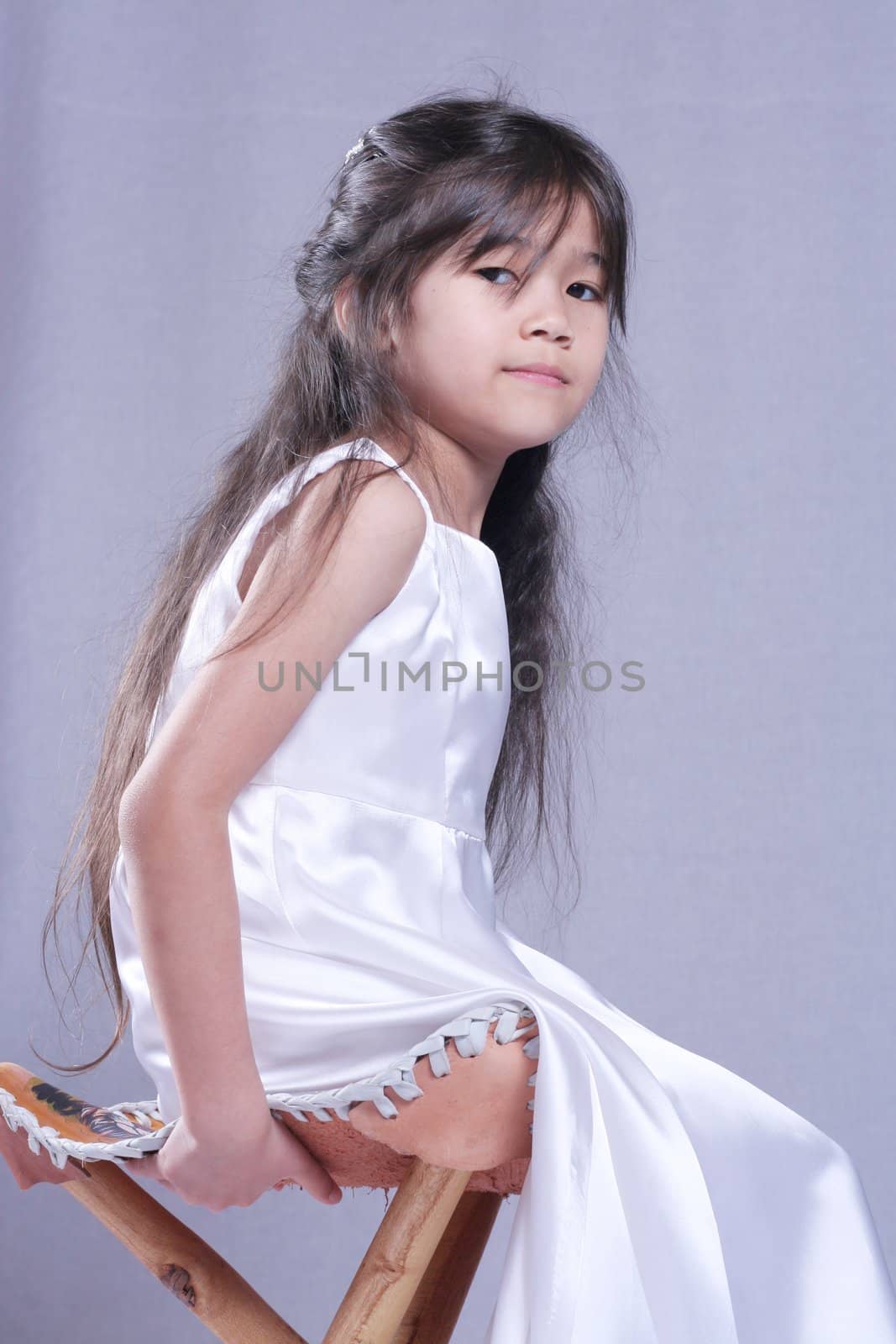 Beautiful little girl in white satin gown . Part Asian, Scandinavian background.