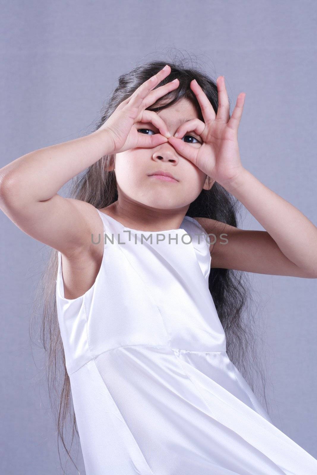 Cute little girl in white satin dress playing with her hands. Part asian, scandinavian background.