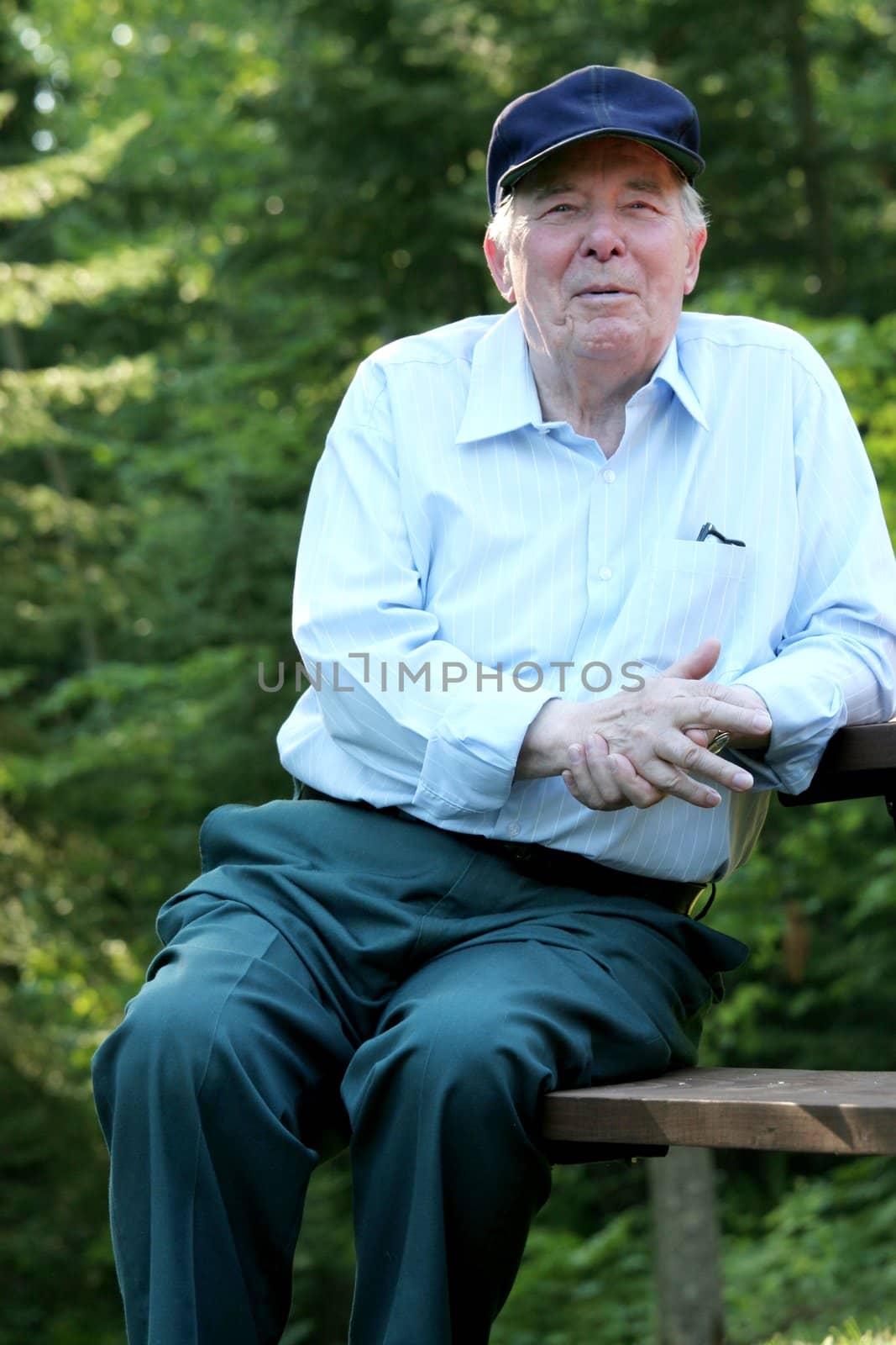 Elderly man enjoying his rest outdoors, while sitting on a picnic bench.