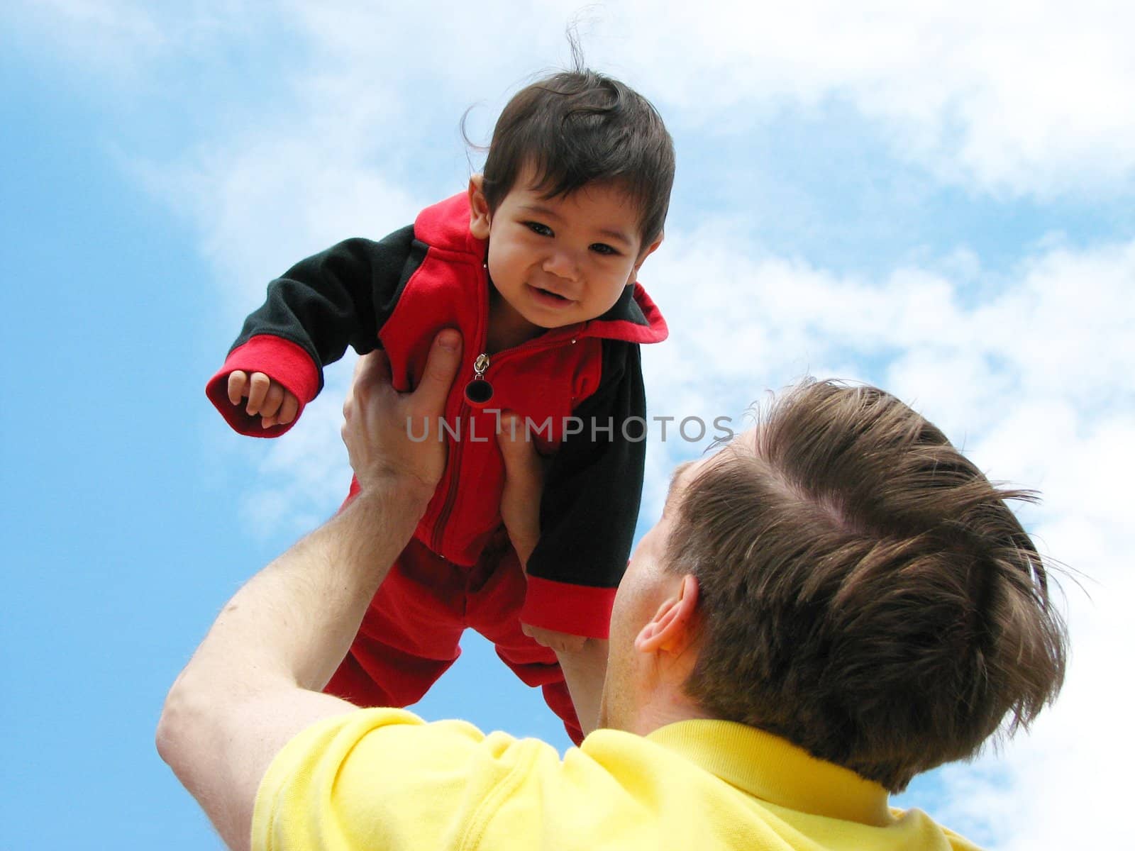 Father holding up his baby boy towards the sky by jarenwicklund
