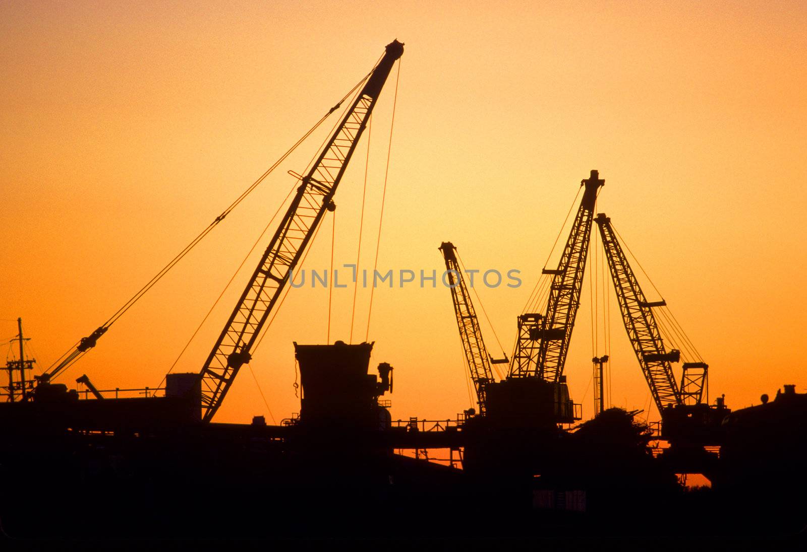 silhouette of industrial cranes at sunset by hotflash2001