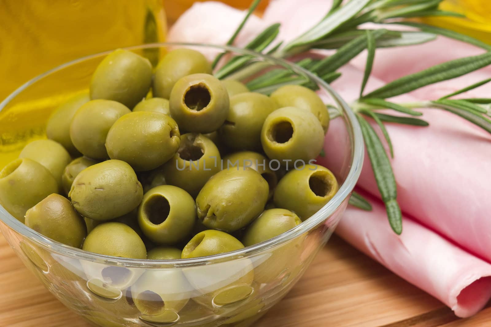 Rolled slices of ham, green olives and rosemary 