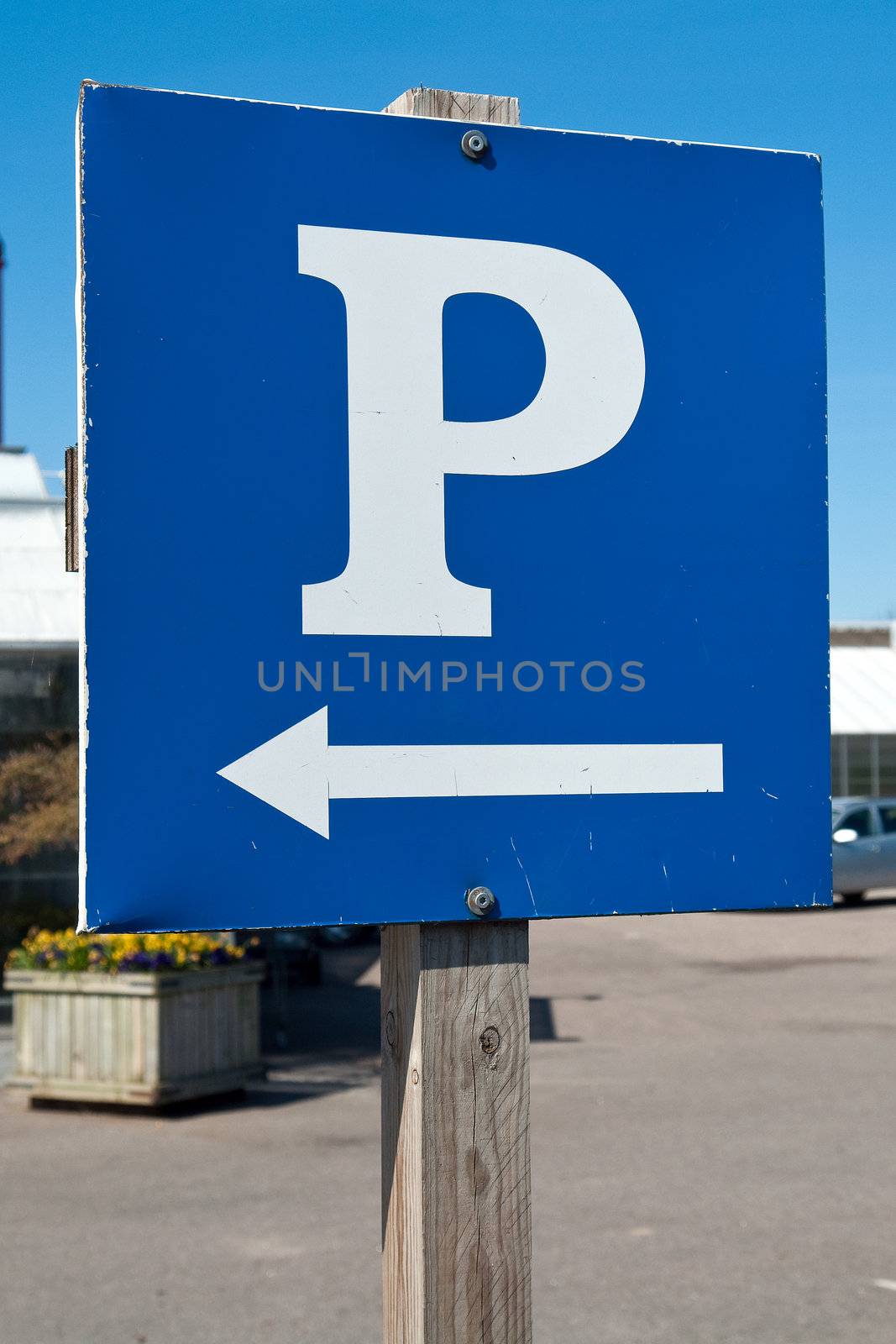 Parking sign with a white 'P' on a blue metal plate with clear blue sky background vertical