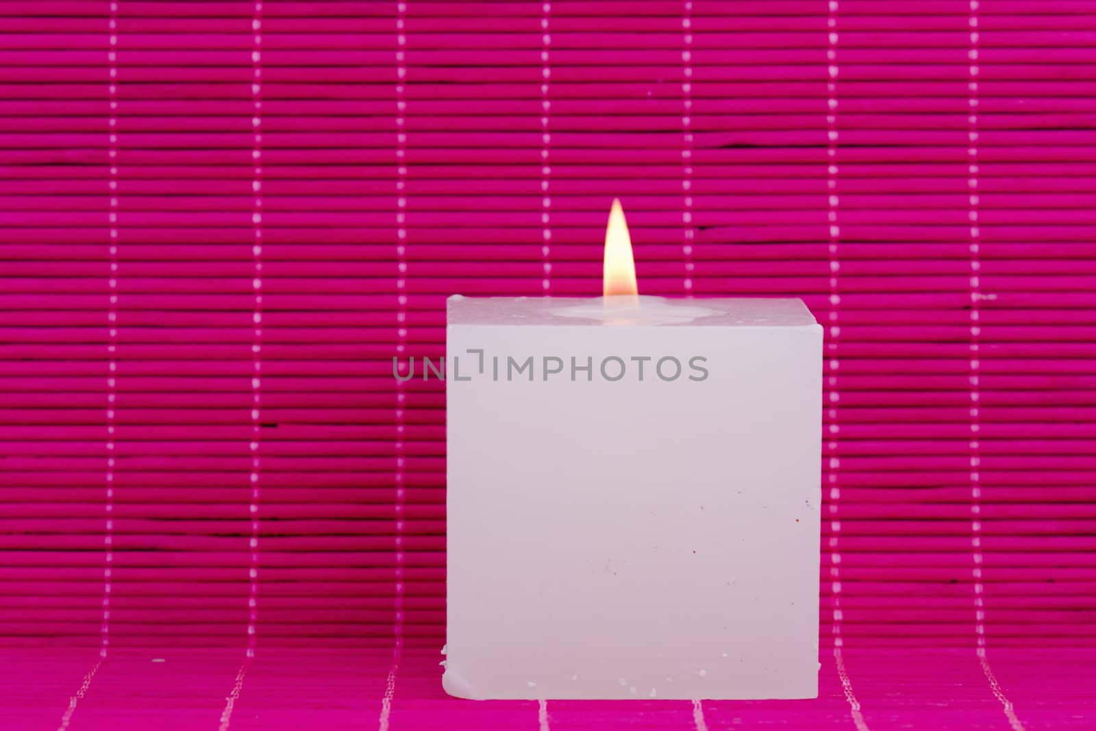 a white candle on pink background