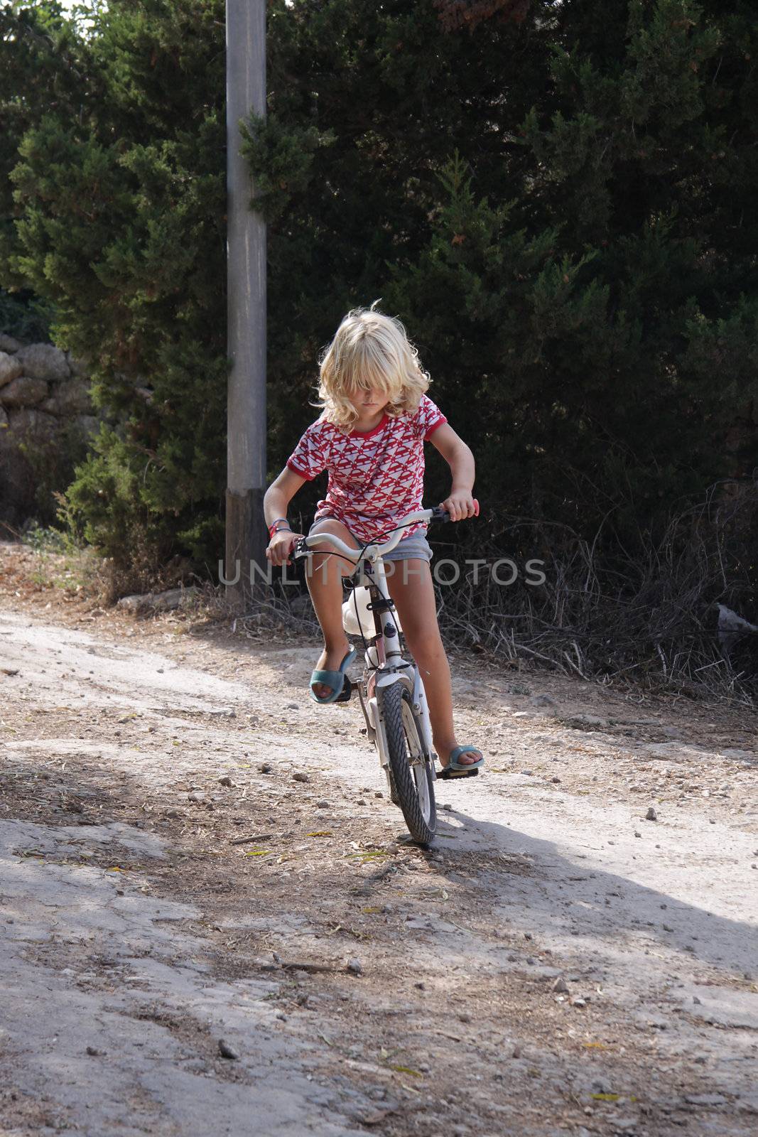 A young girl is struggling with learning to ride her bike. She is very concentrated