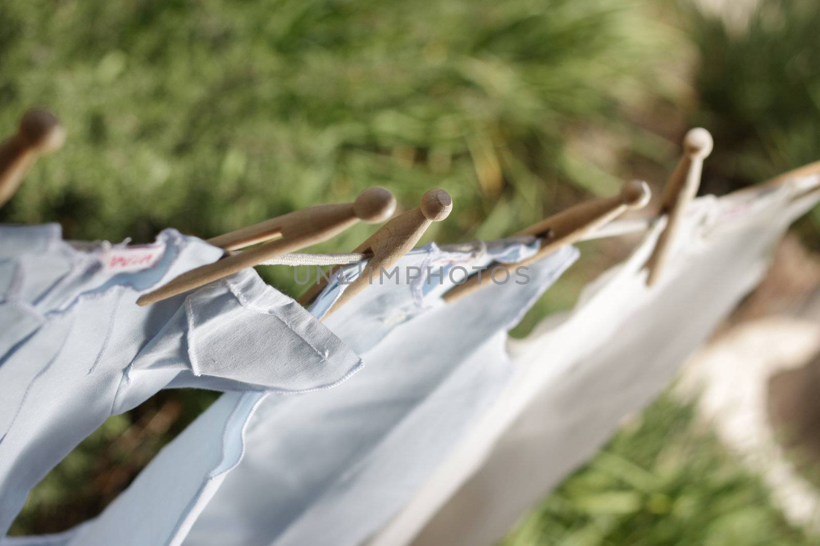 Beautiful children's clothes pegged up with old fashioned wooden pegs drying outside. Soft focus, sharpness on pegs
