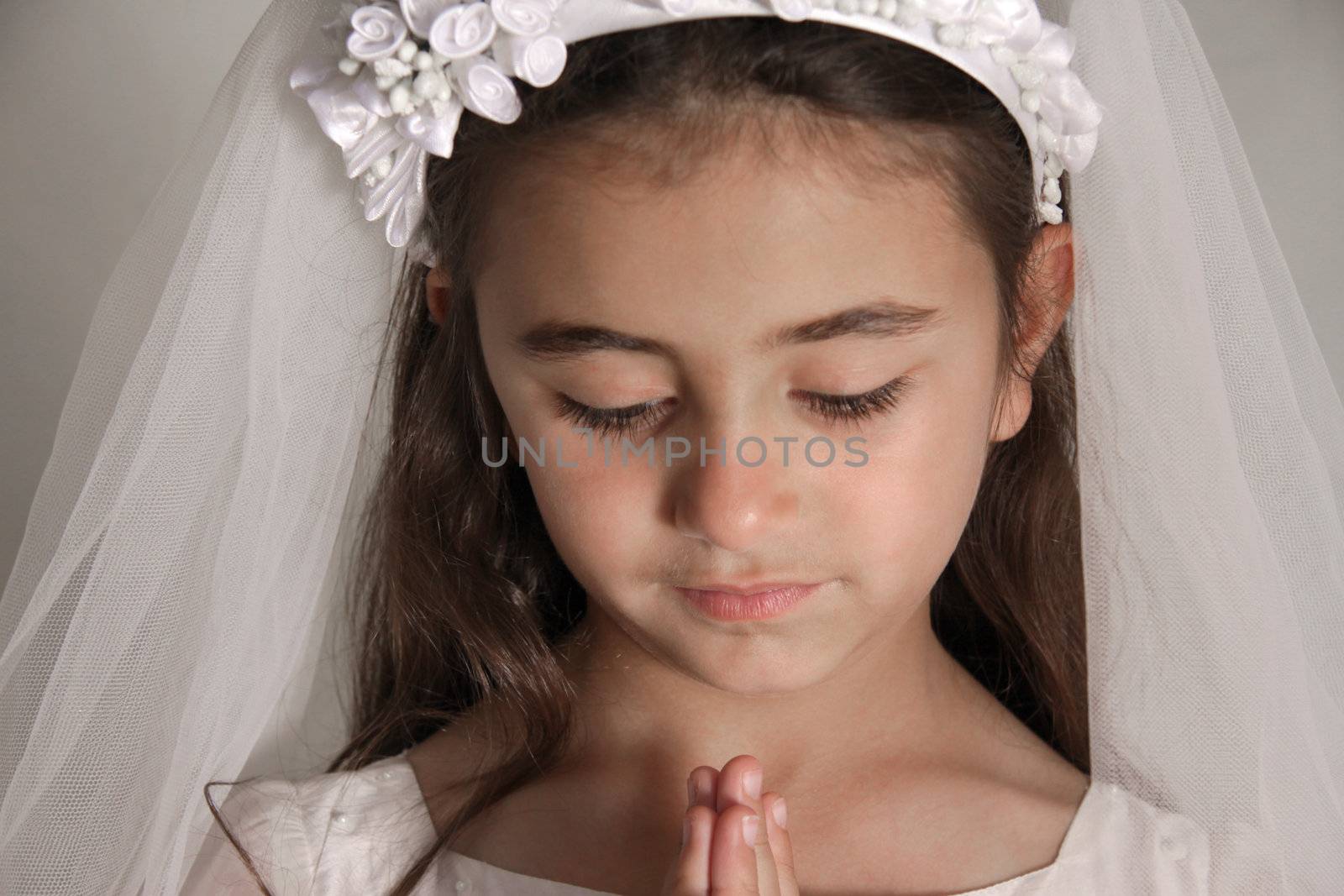 A young girl praying during her first communion celebration