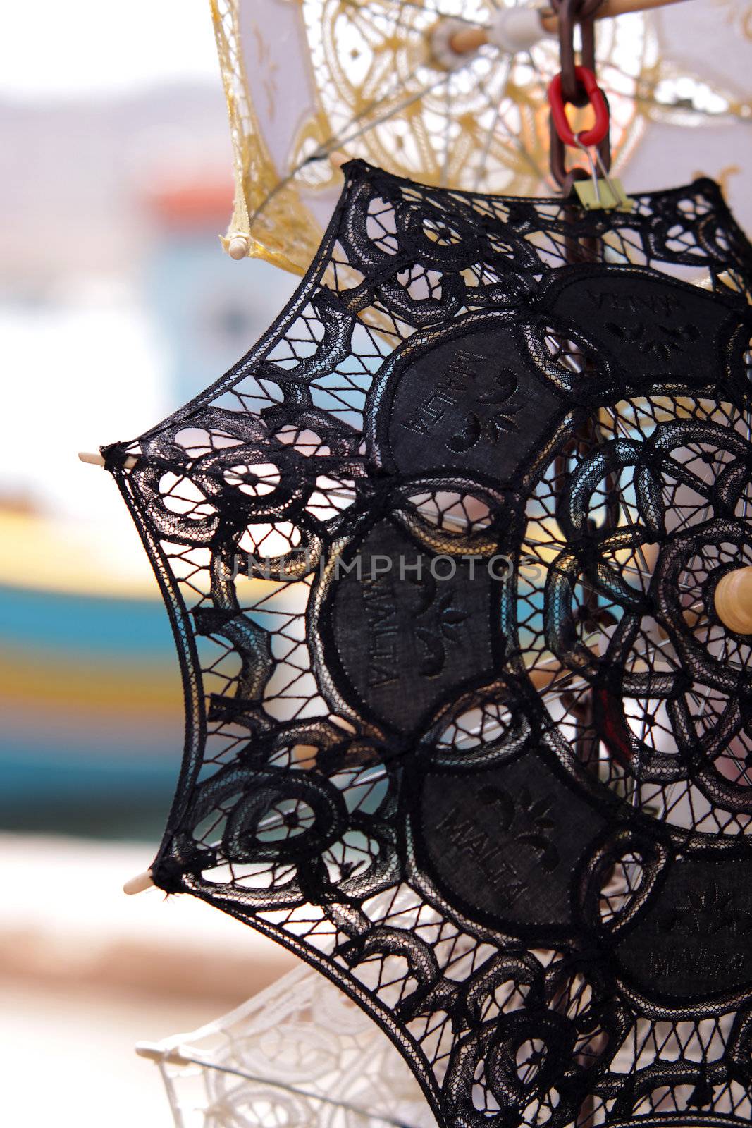 Detail of a black decorative lace umbrella found in a Maltese souvenir market held in Marsaxlokk harbour. Background blurred out. Vertical photo