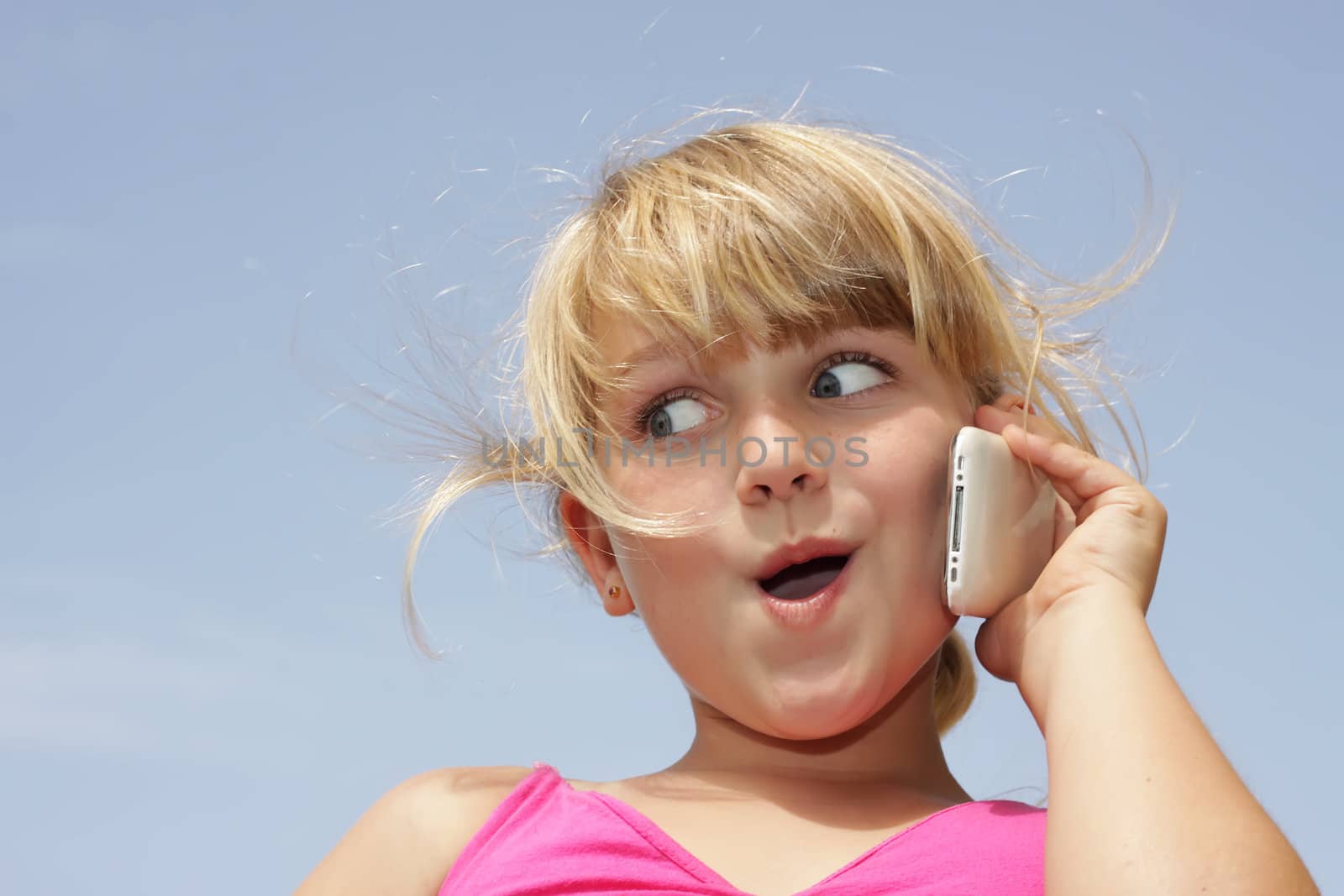 A young girl is doing a funny face while talking on her touch phone