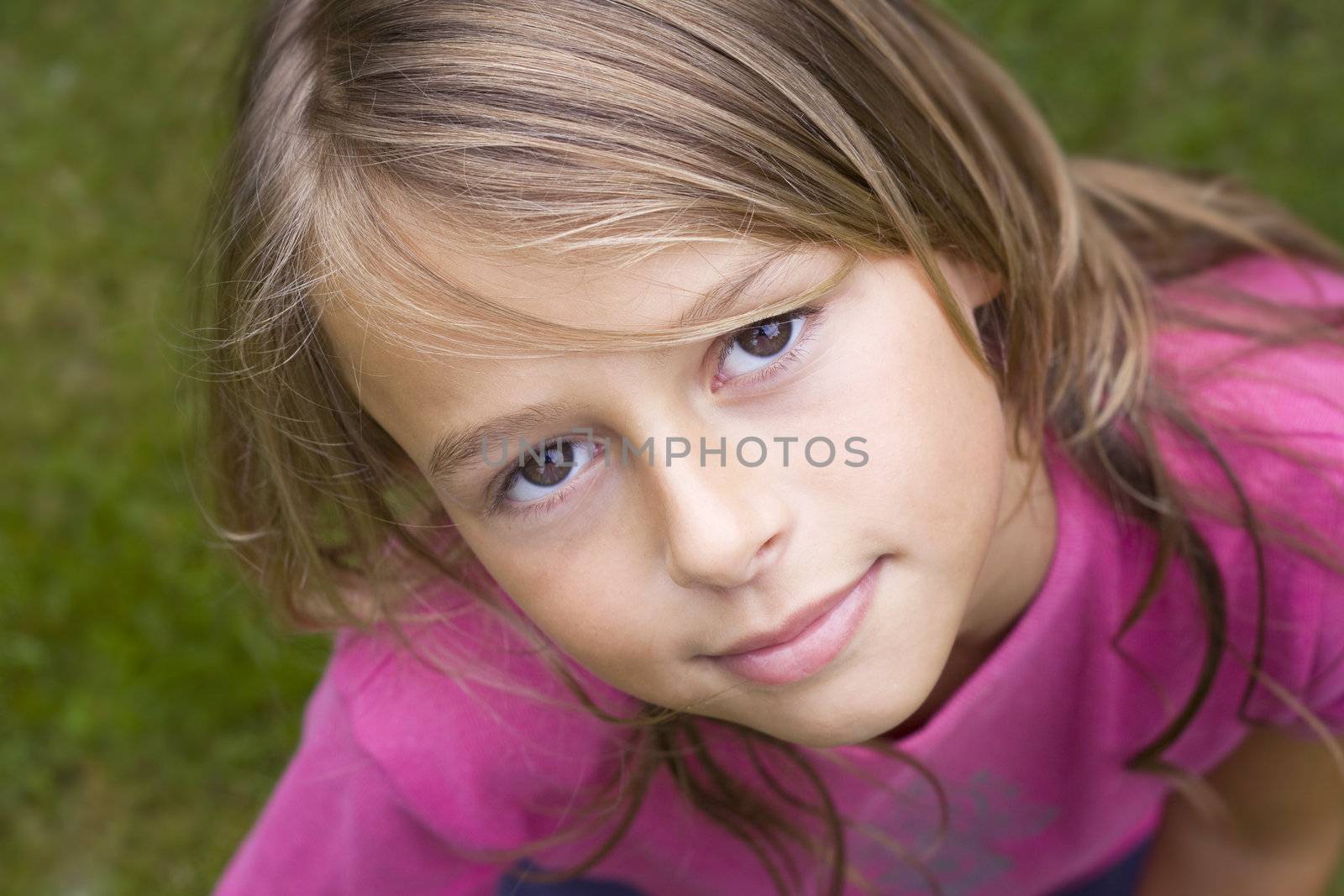 Close up portrait of a ten year old girl, smiling up at the camera. Positive emotion