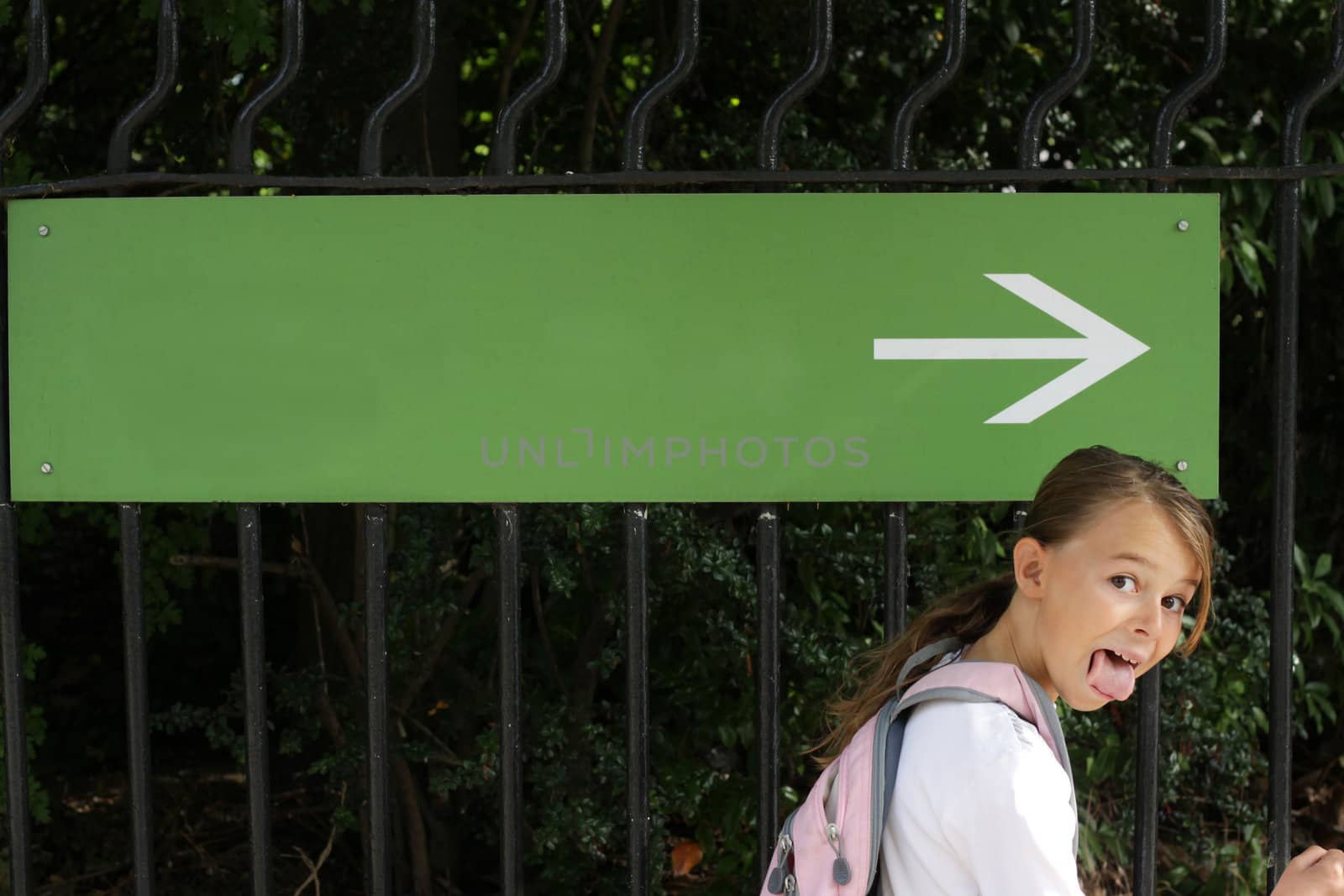 Girl doing a funny face next to a sign with an arrow showing the direction