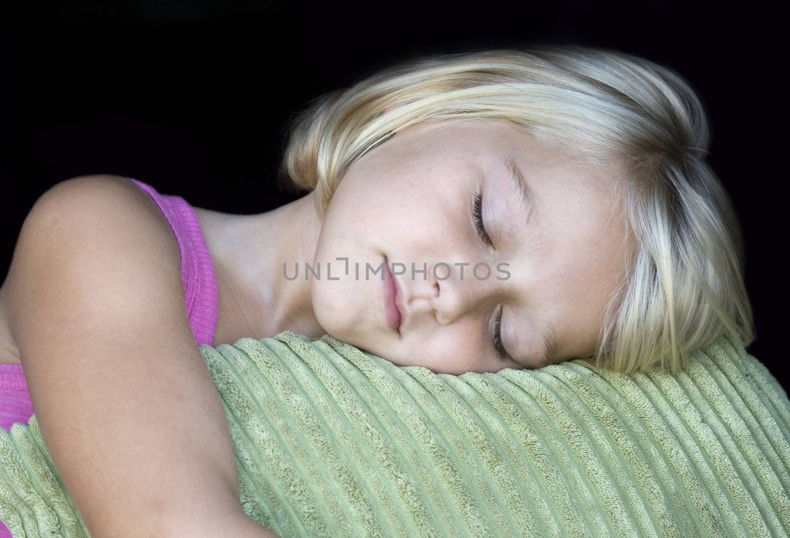 Girl sleeping on a corderoy green pillow. Isolated on black. Peaceful feeling