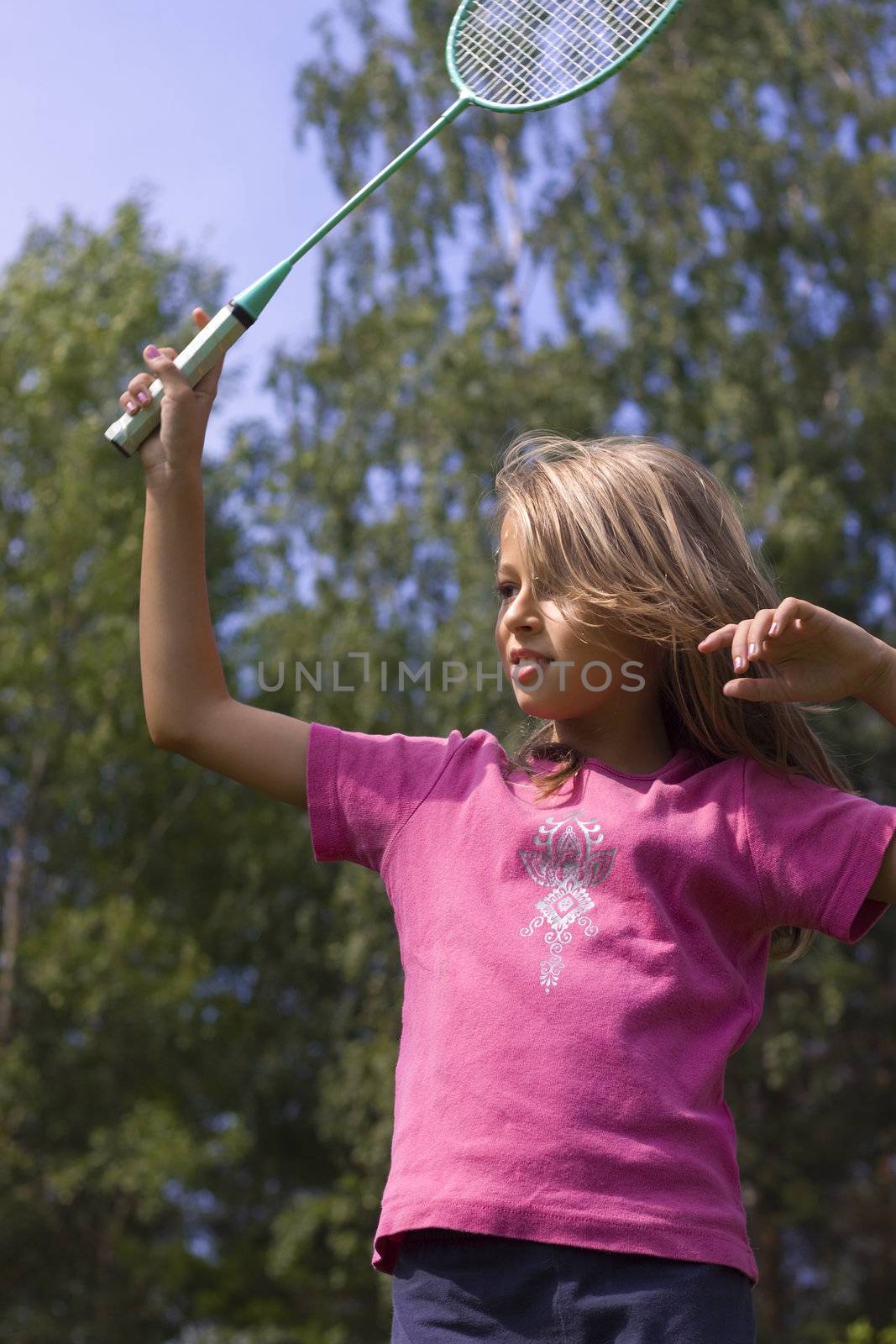 Girl playing with racket on the lawn in summer