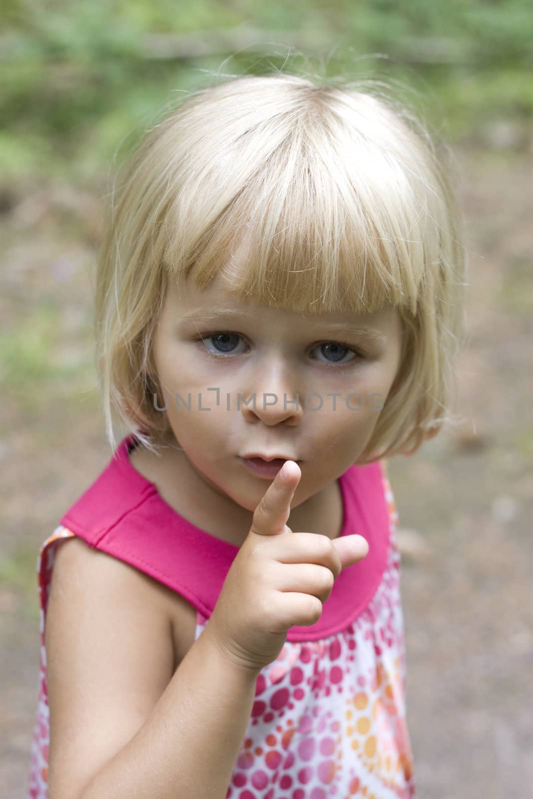A 3 year old little girl holding up her finger for silence