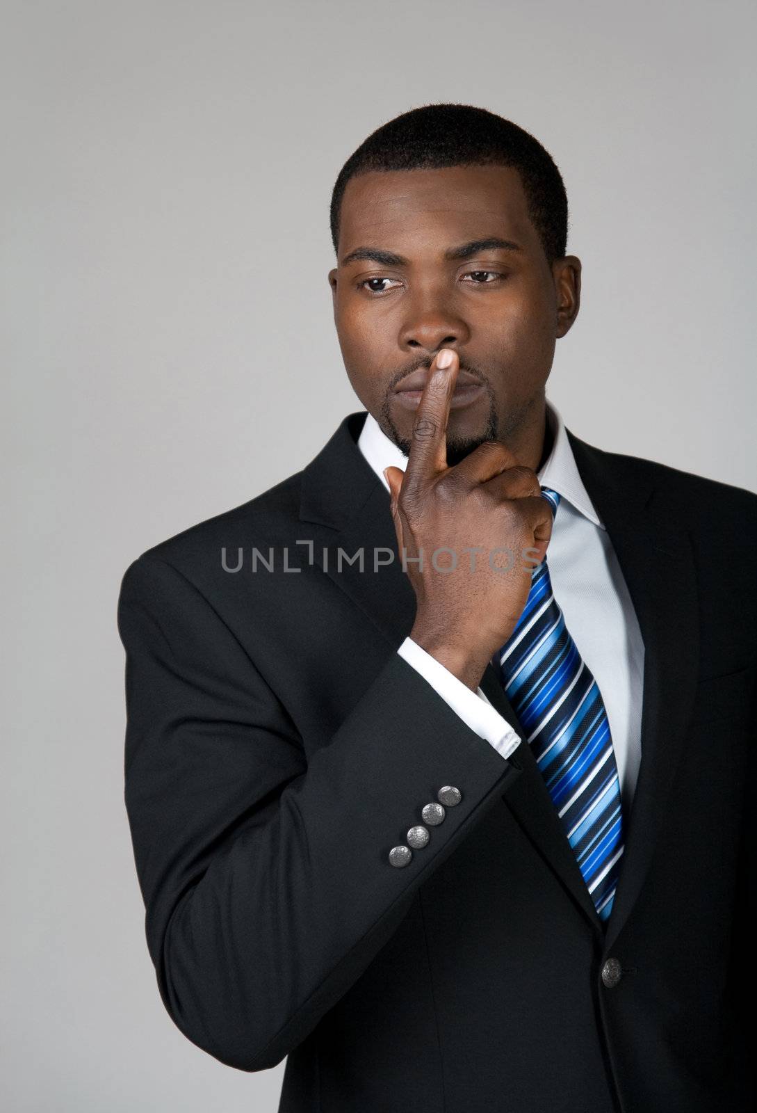 African American business man thinking and holding a finger on his lips.