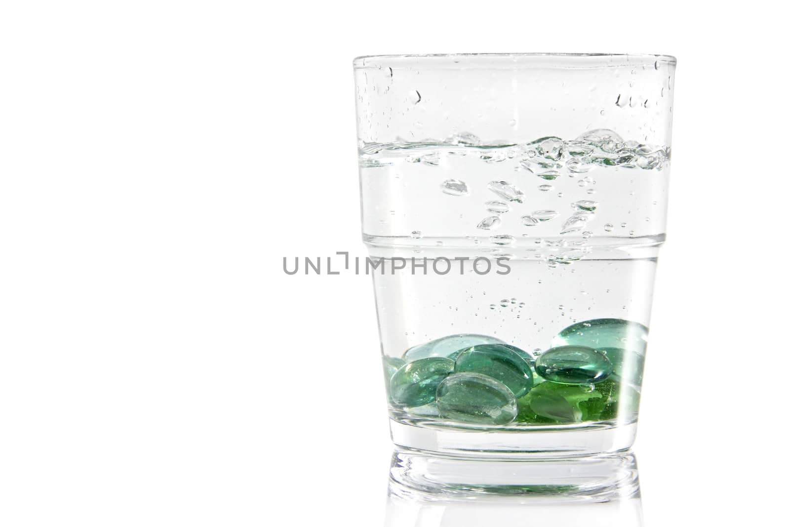 Marbles creating bubbles and a splash while being dropped in a glass of water. 